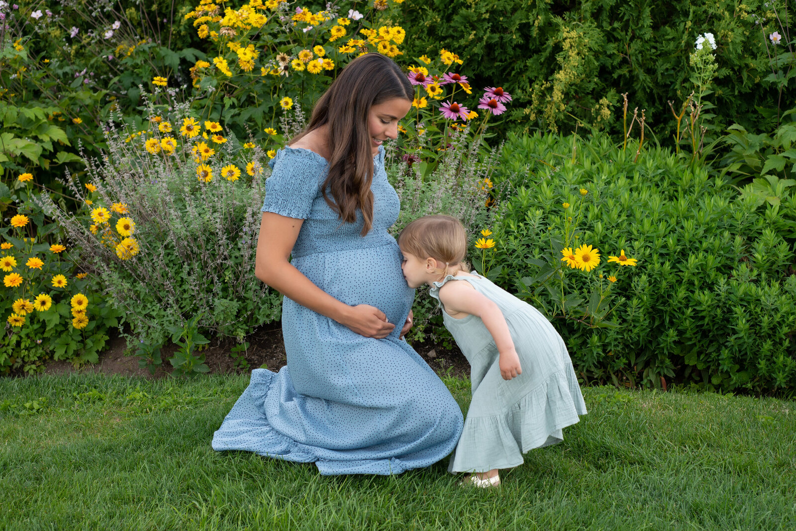 Baby kissing mothers pregnant belly in Ogunquit Maine garden