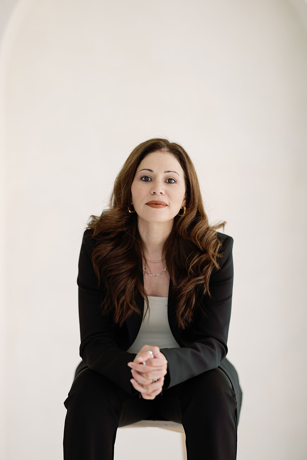 Sophisticated business portrait of a woman sitting in a tailored black suit, perfect for executive headshots in Washington, DC.