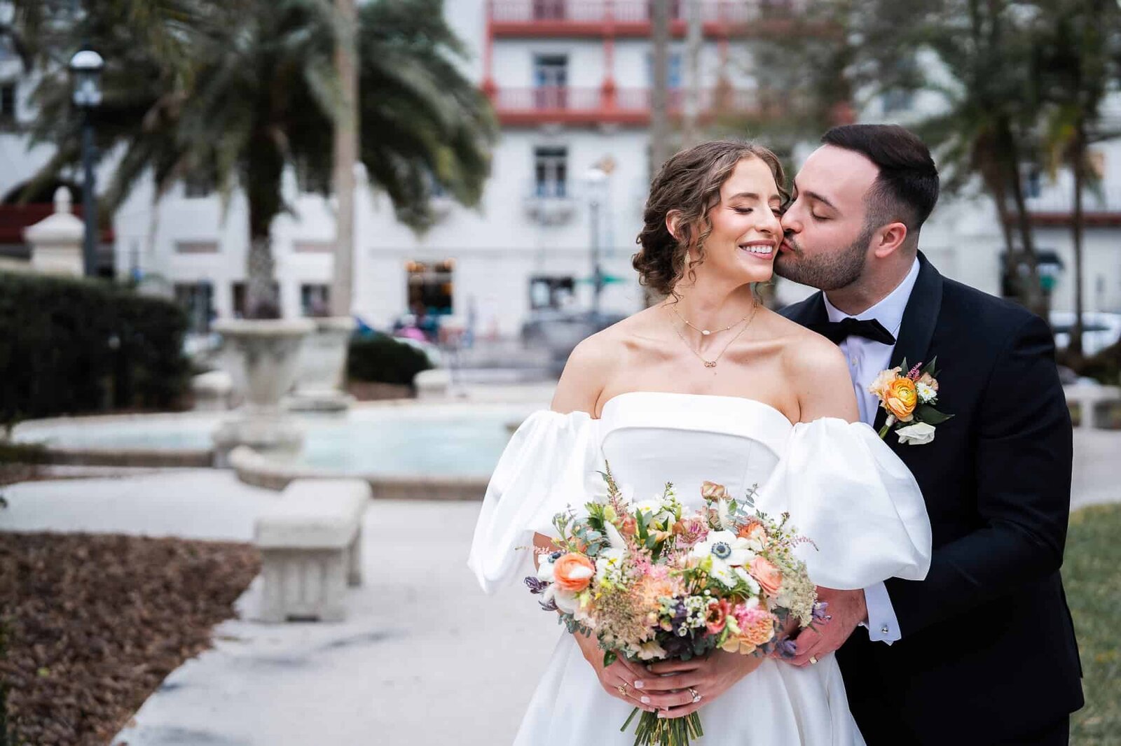 Groom is kissing his bride's cheek at Casa Monica Wedding Venue in St Augustine