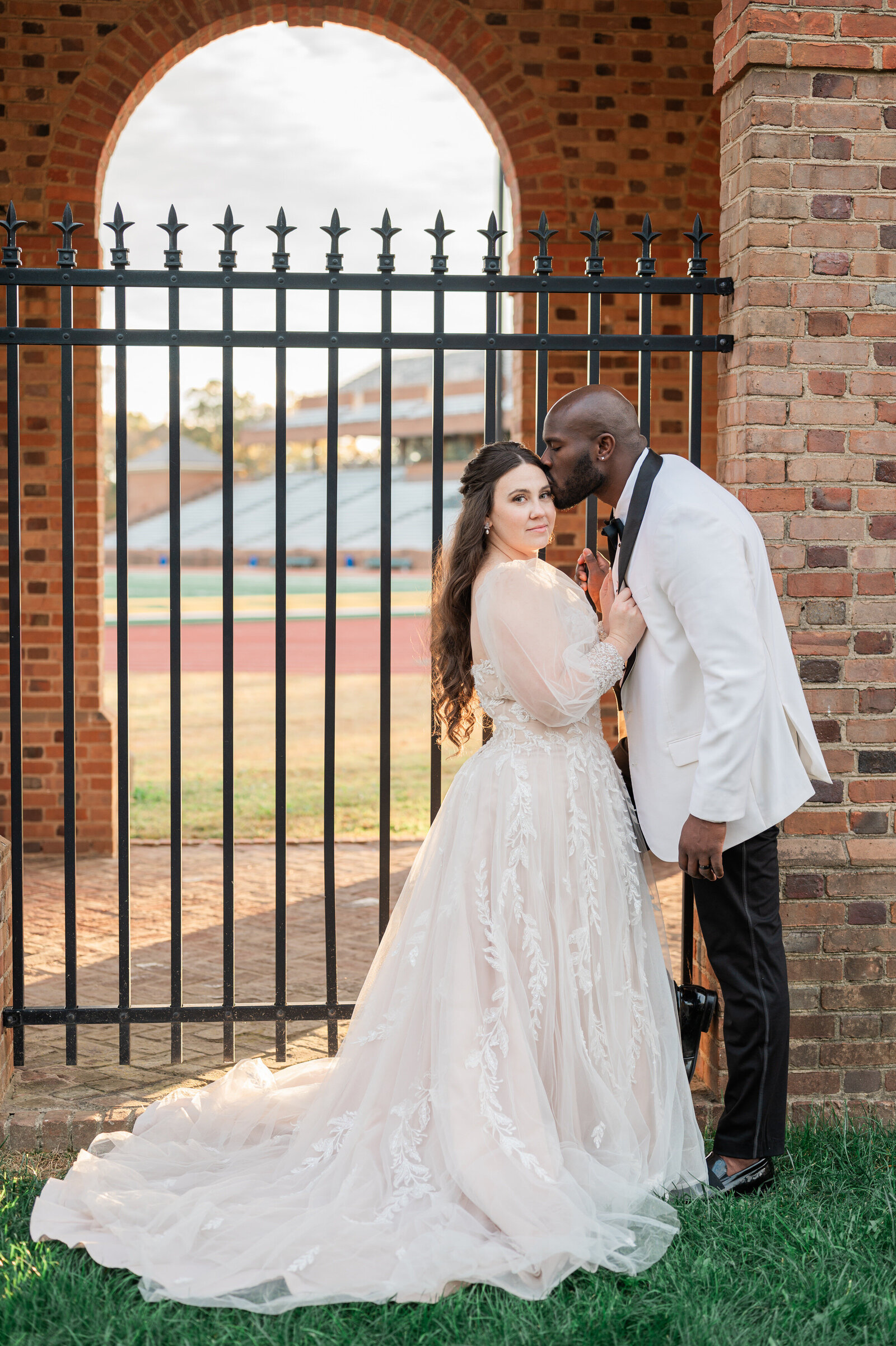 A person kissing their partner's head on their wedding day