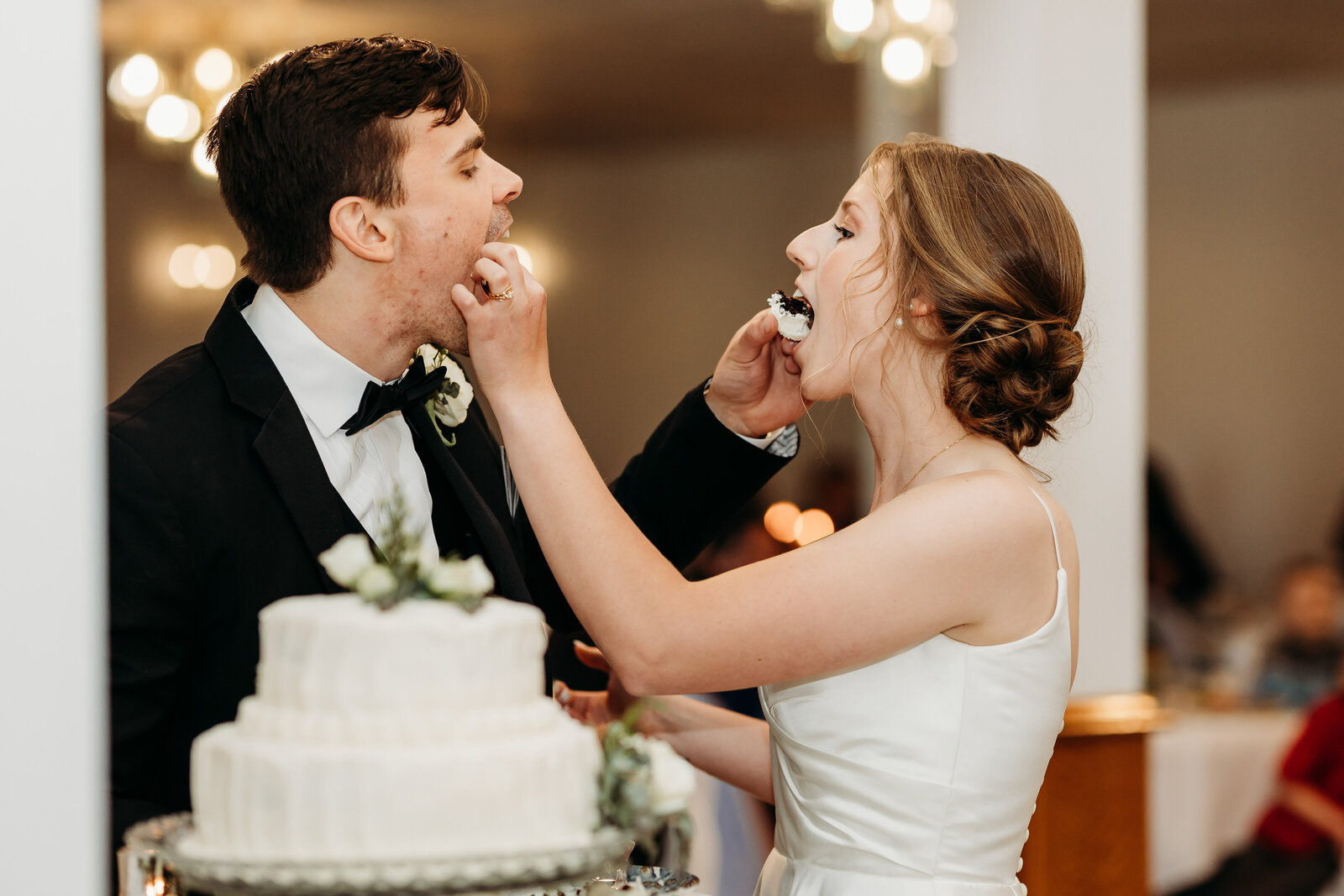 Newly wed couple feed each other  a piece of cake