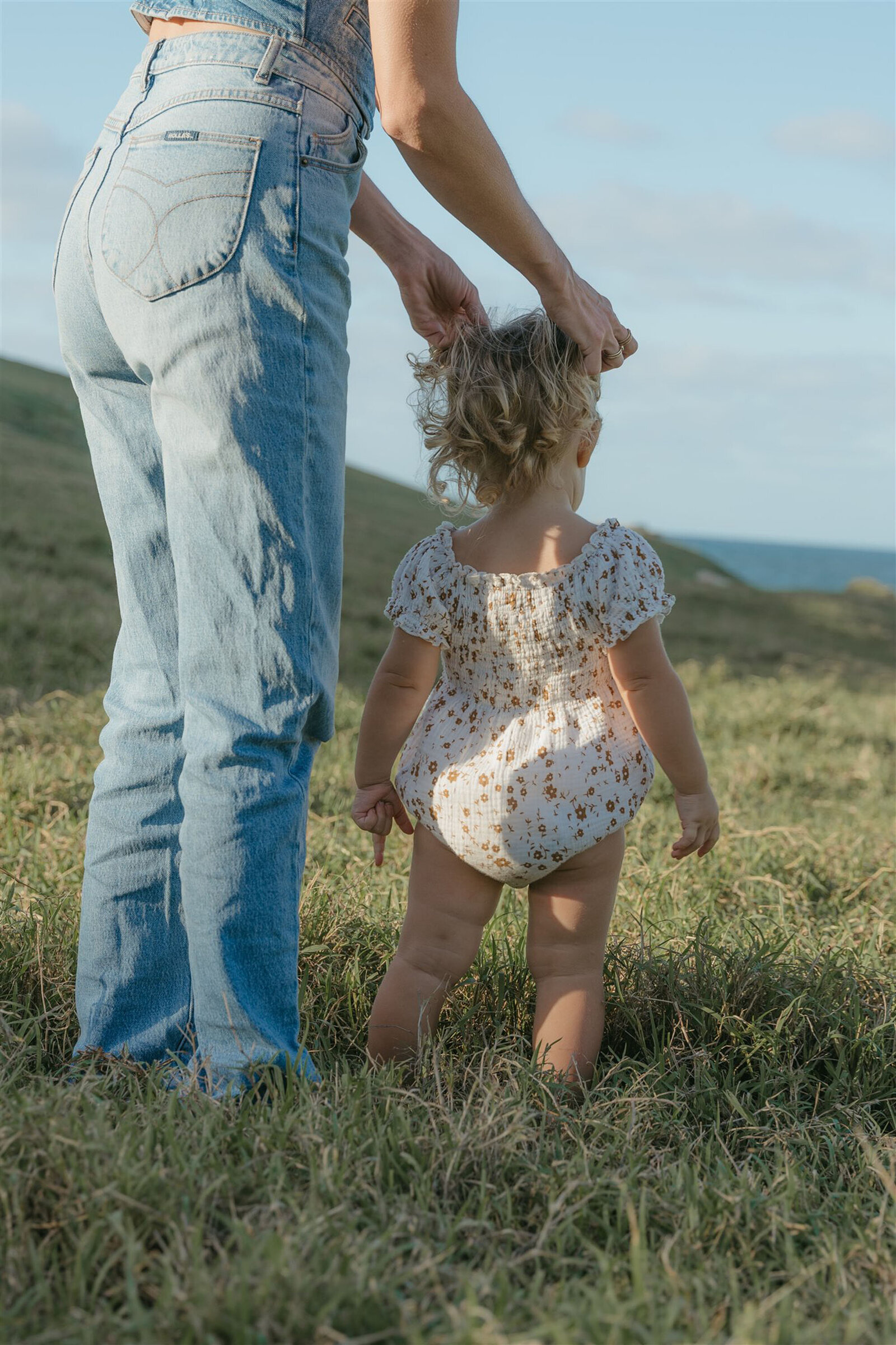 Styled Maui family photography session on a cliffside, capturing play and connection in denim and neutral tones.