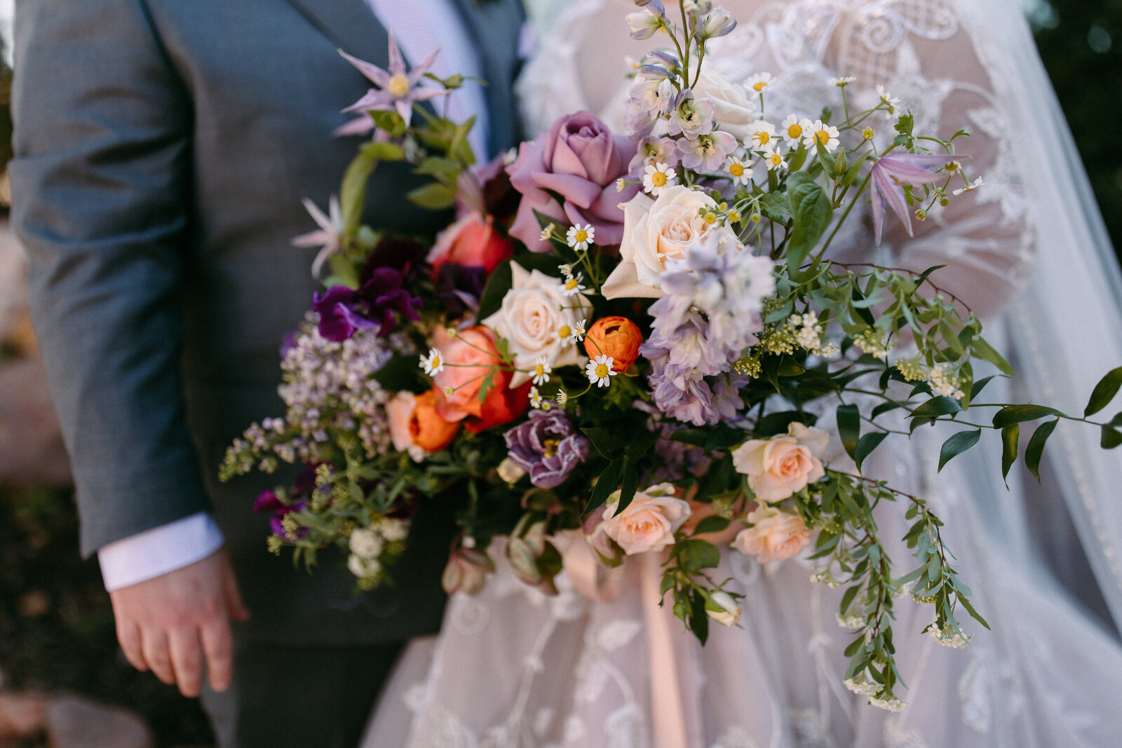 Purple and green wedding bouquet held by bride and groom with faces out of frame, floral design by The Floral Eclectic in Dallas, Texas
