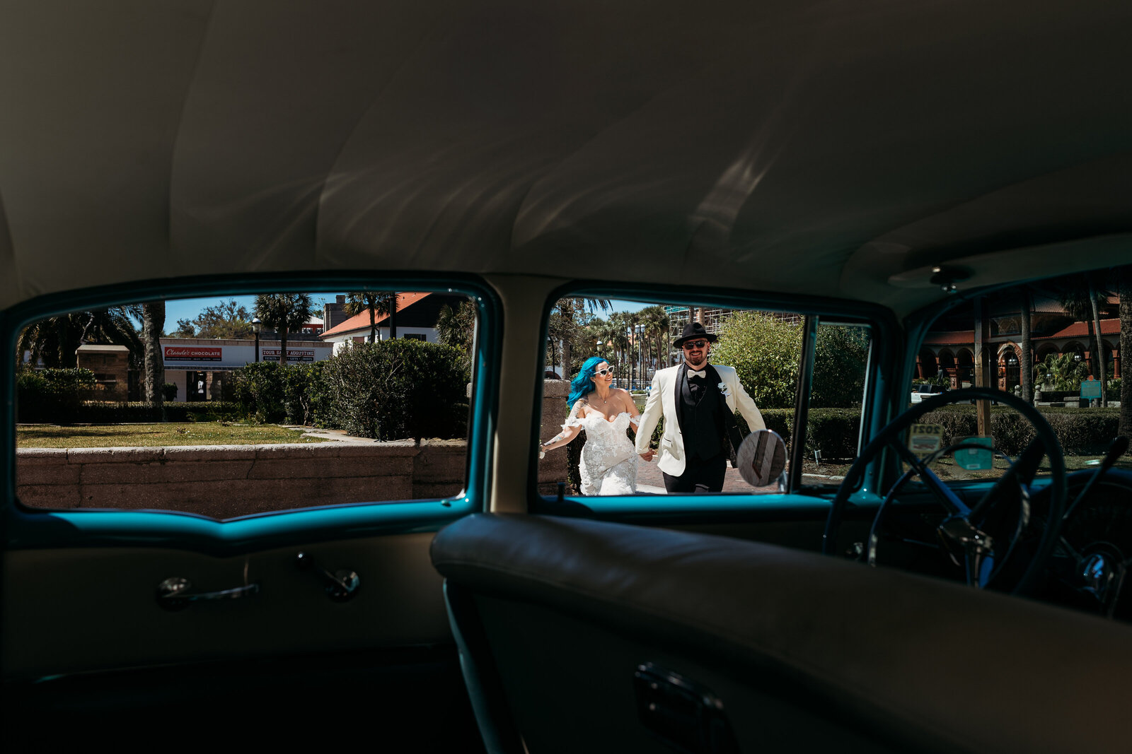 Creative wedding photo of bride and groom through a vintage car window with downtown St. Augustine architecture in the background.