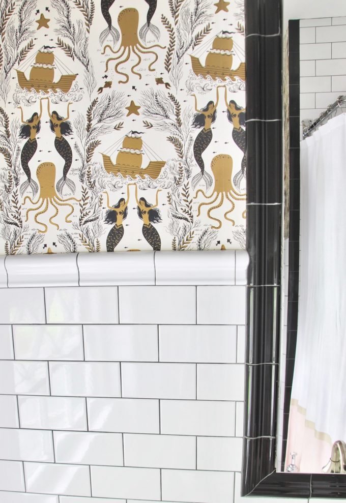 A wallpapered bathroom with subway tile.