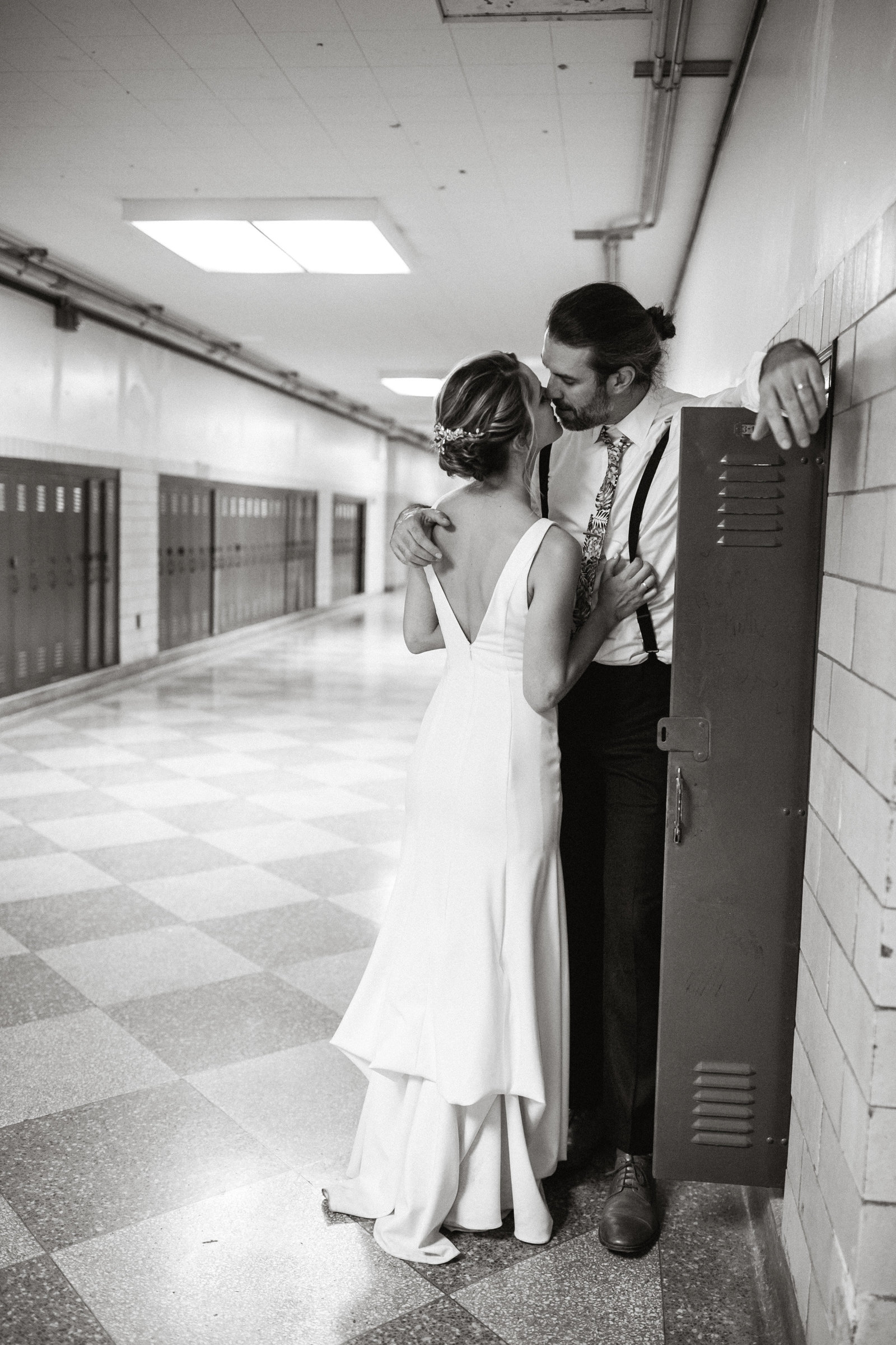 Bride and groom close the night with a kiss, alongside old school lockers at this unique wedding venue.