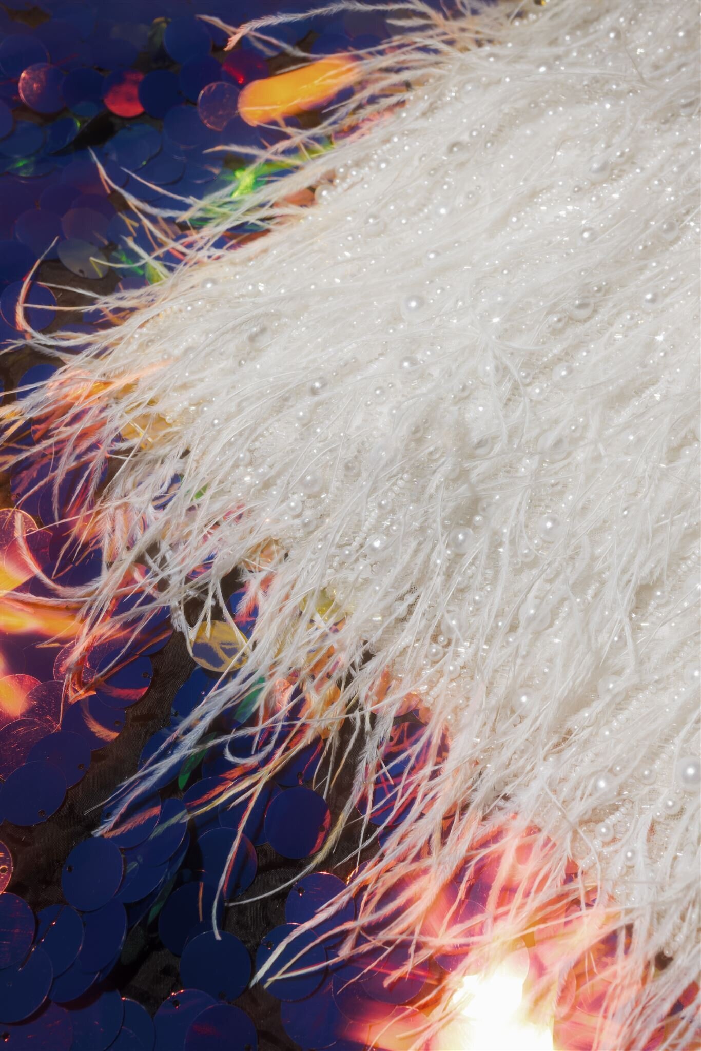flat lay image of a feather sparkle dress with a multicolor sequin backdrop