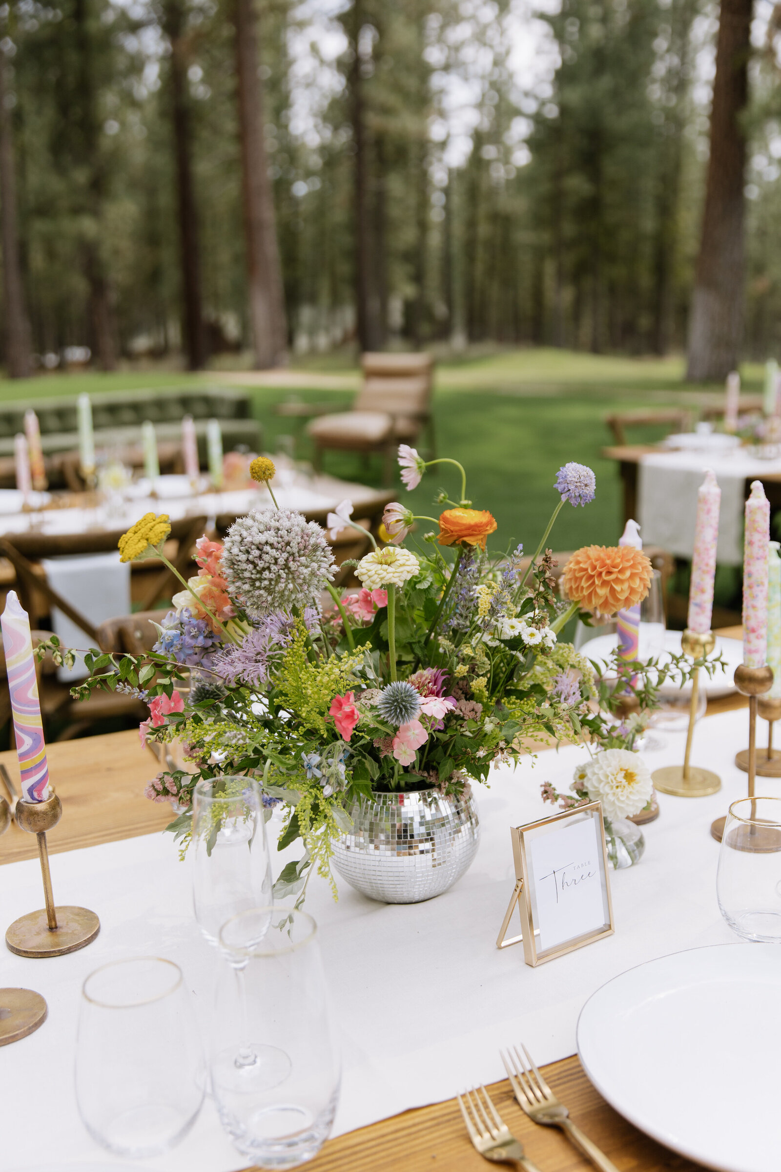 Eclectic wedding tablescape with retro candles, colorful florals, and disco ball accents in Tahoe woods