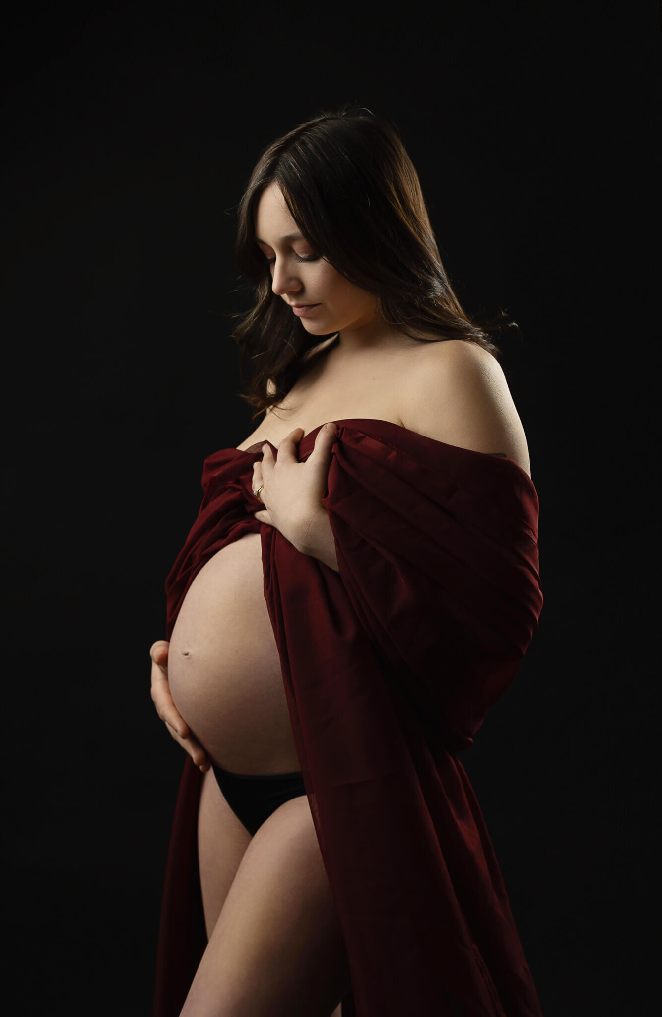 Maternity photoshoot in Austin of a woman wearing black lingerie and a red dress