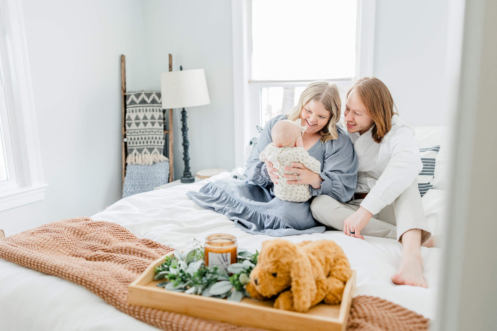 Mom and dad smile at their newborn on a bed