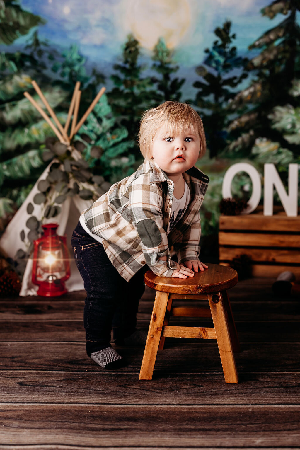 Adorable blonde baby holds himself up on a small stool