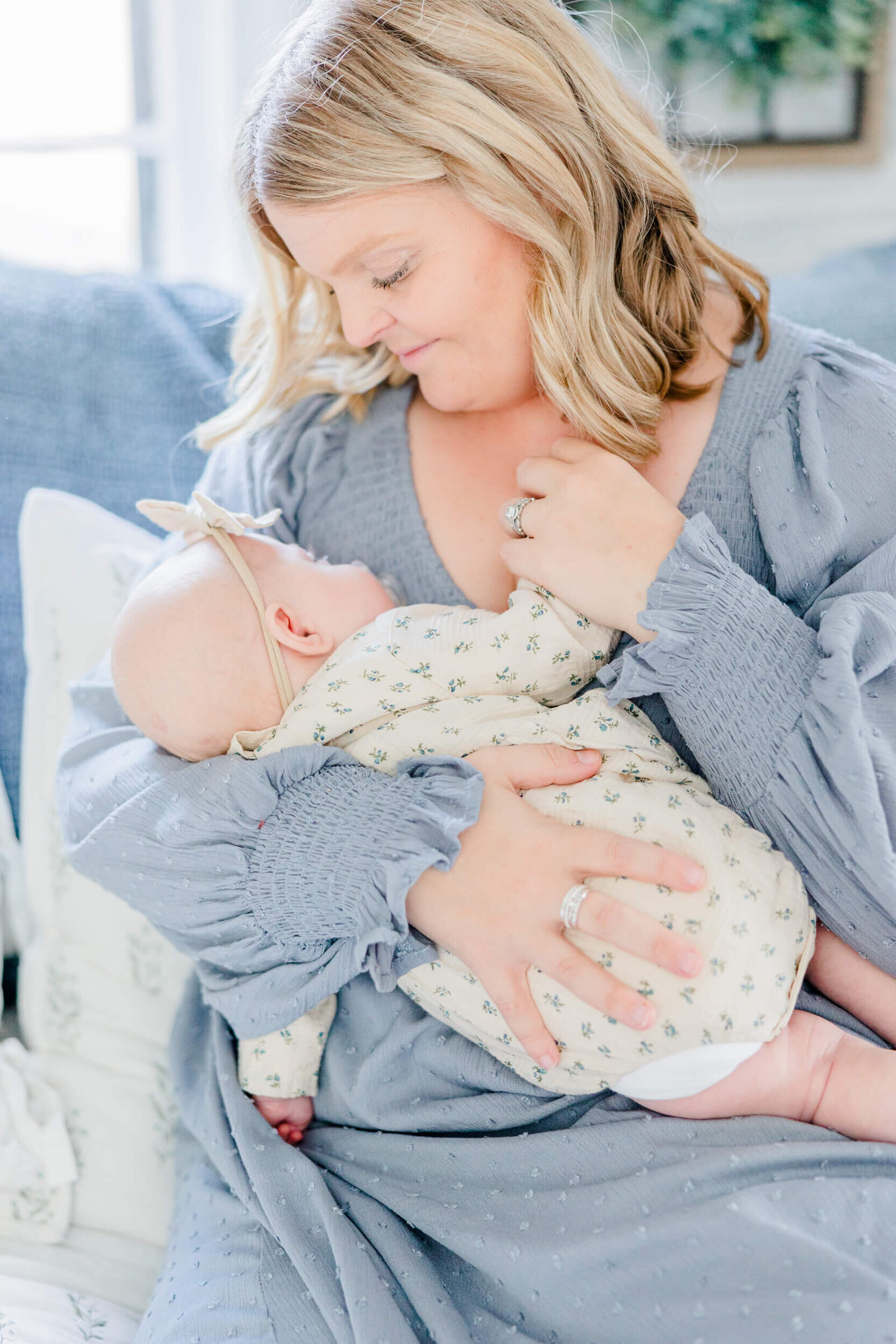 Mom looks lovingly down at the newborn in her arm and holds her hand