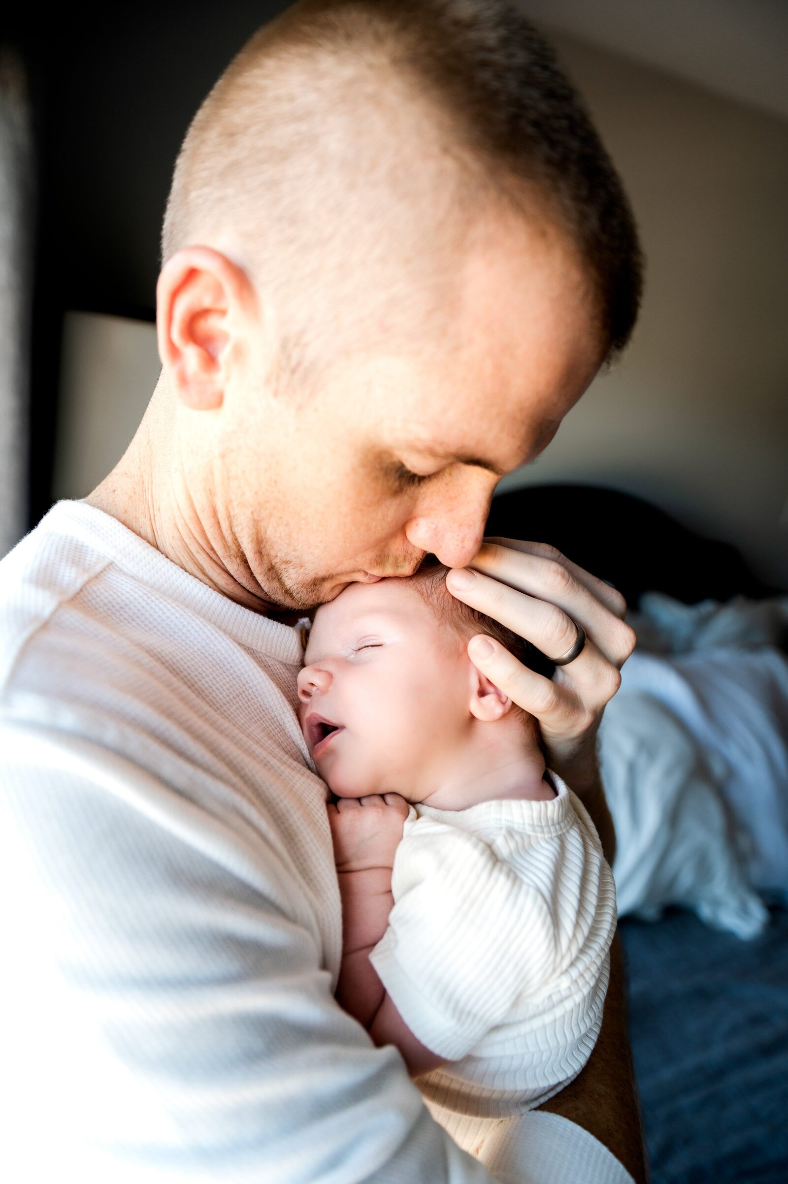 dad holding and kissing his newborn son