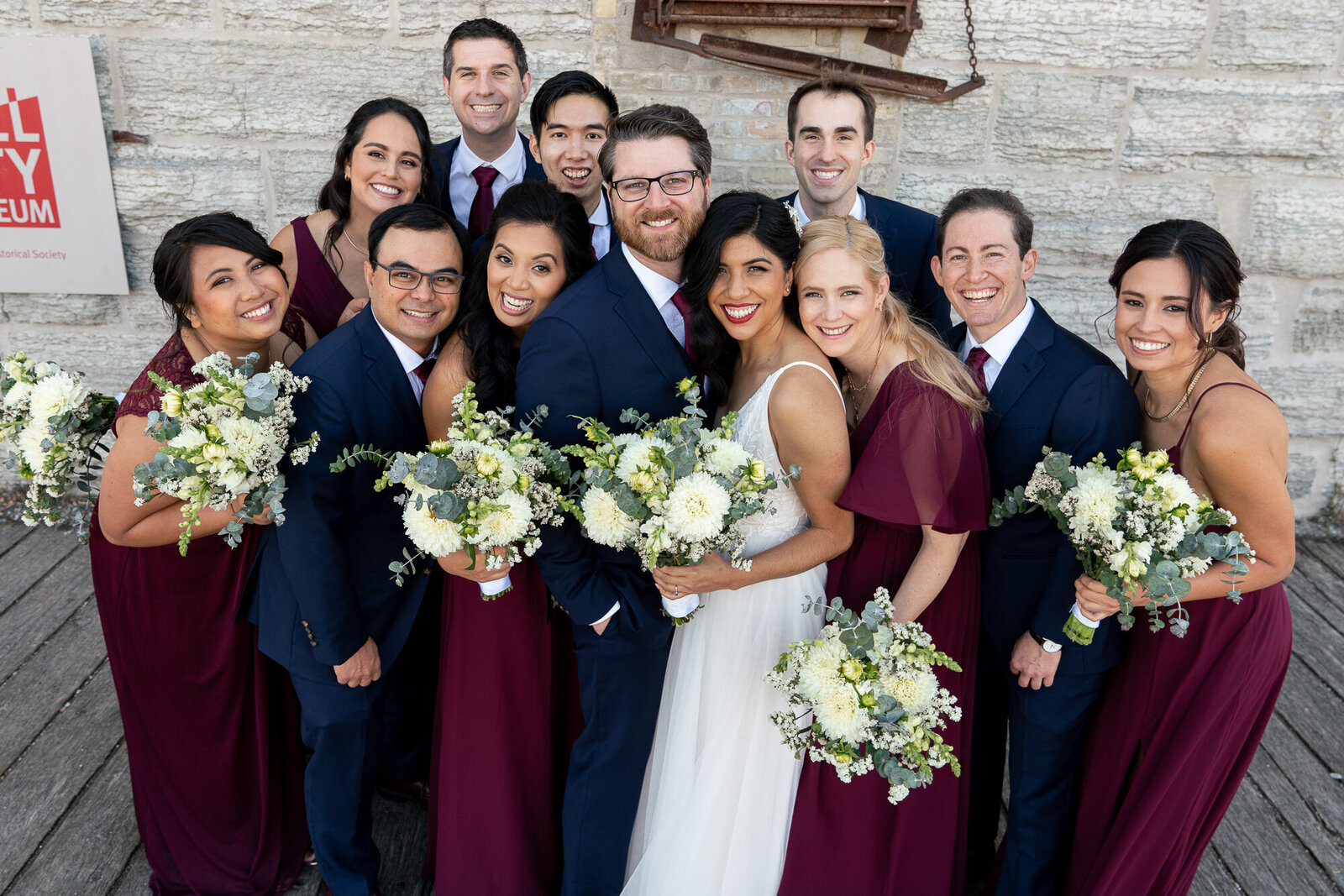 Wedding party smiles and snuggles with bride and groom at Mill City Museum in Minneapolis, Minnesota.