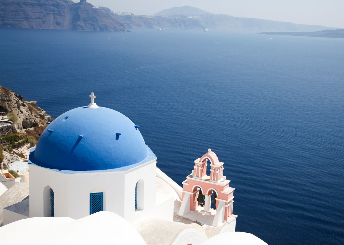 The coast in Santorini with the view of a white church with a dome