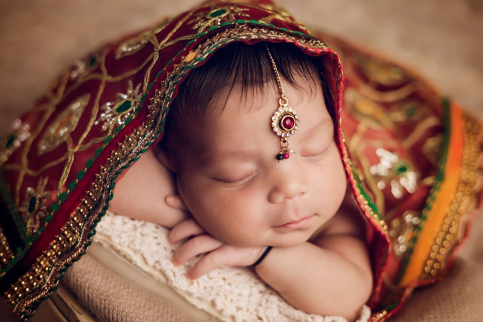 Newborn girl in a red and gold sari, captured by Bia Schaefer, Orlando newborn photographer during an in-home session.