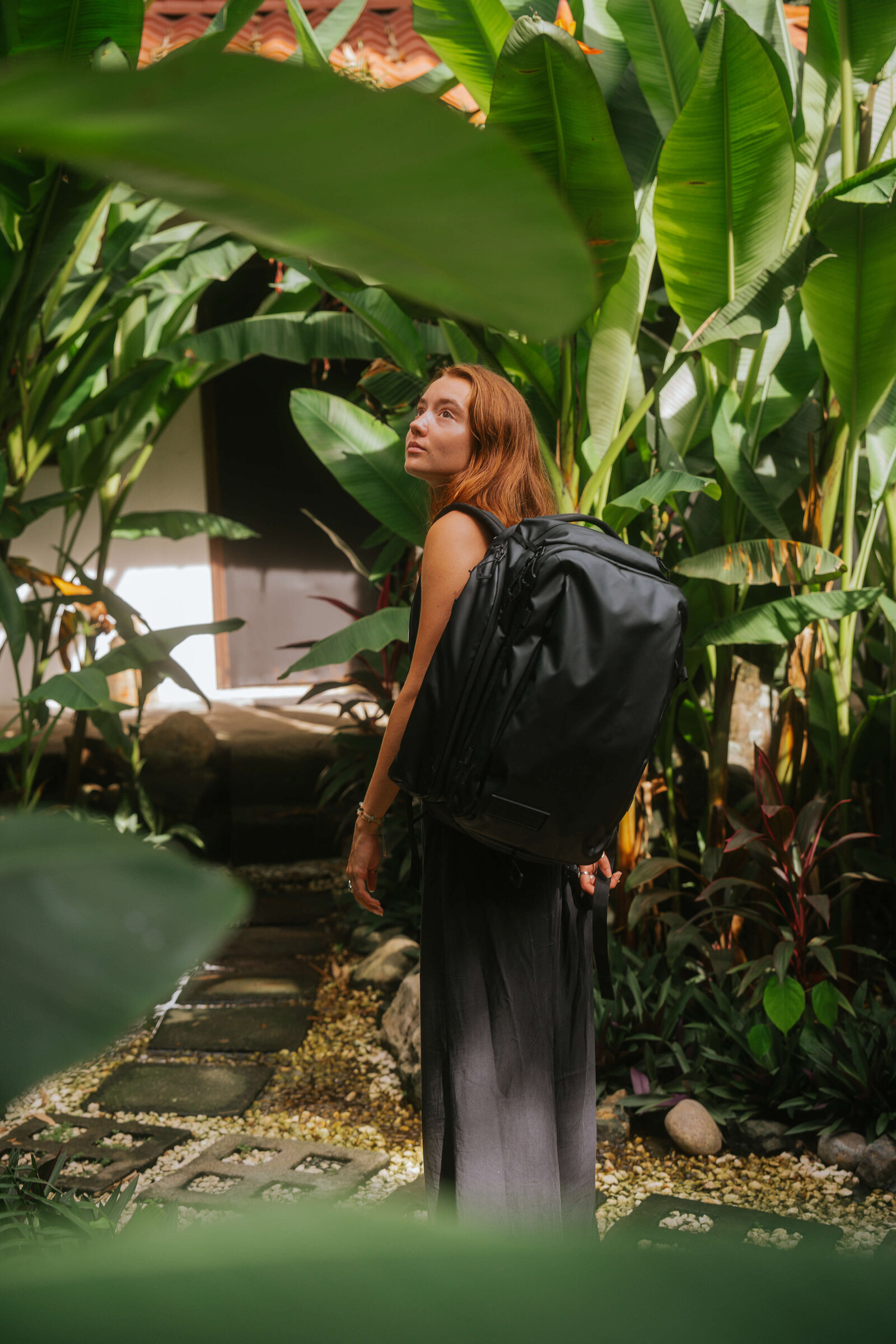 Girl with travel backpack in lush greenery