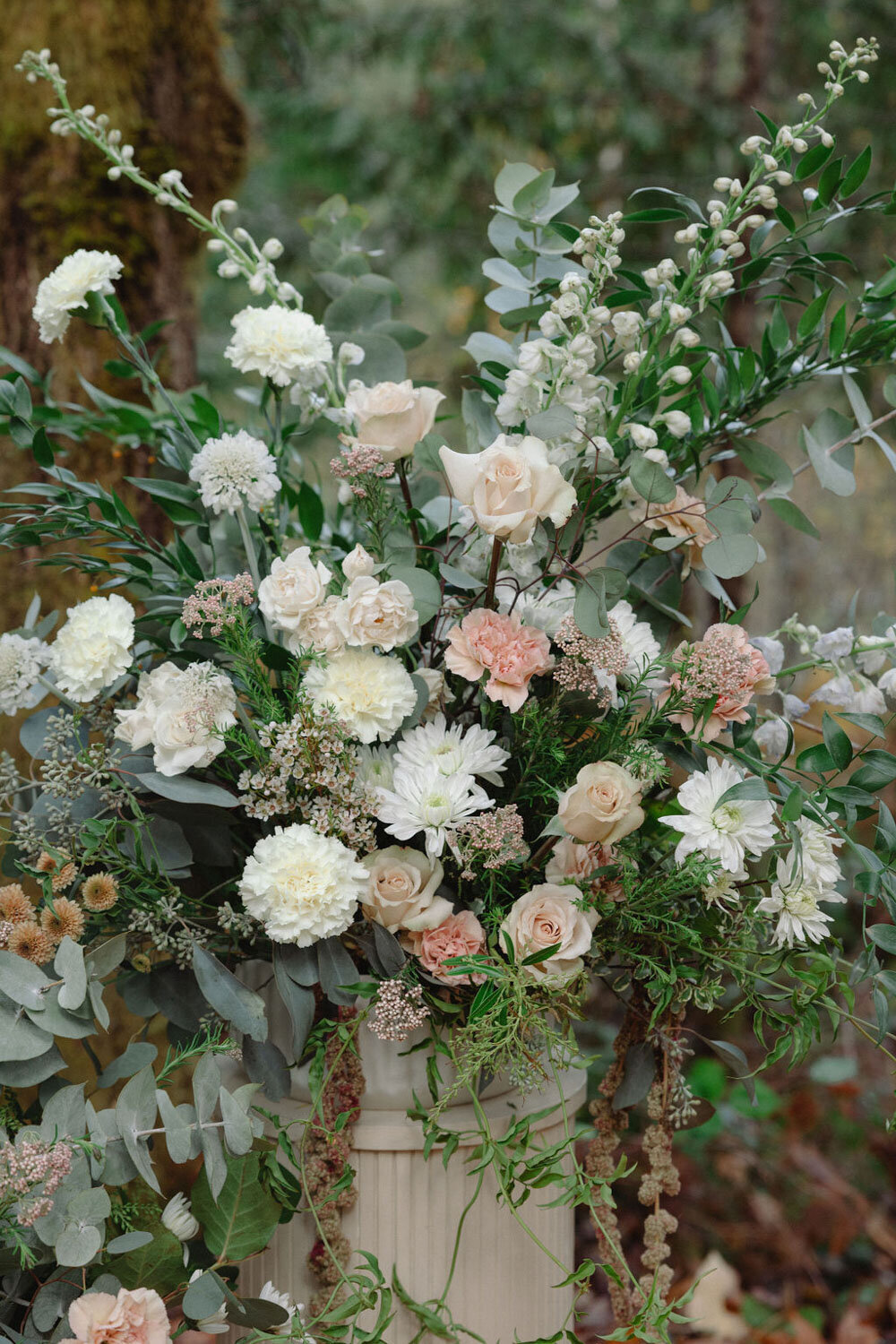 Lush wedding ceremony floral arrangement with white and blush blooms