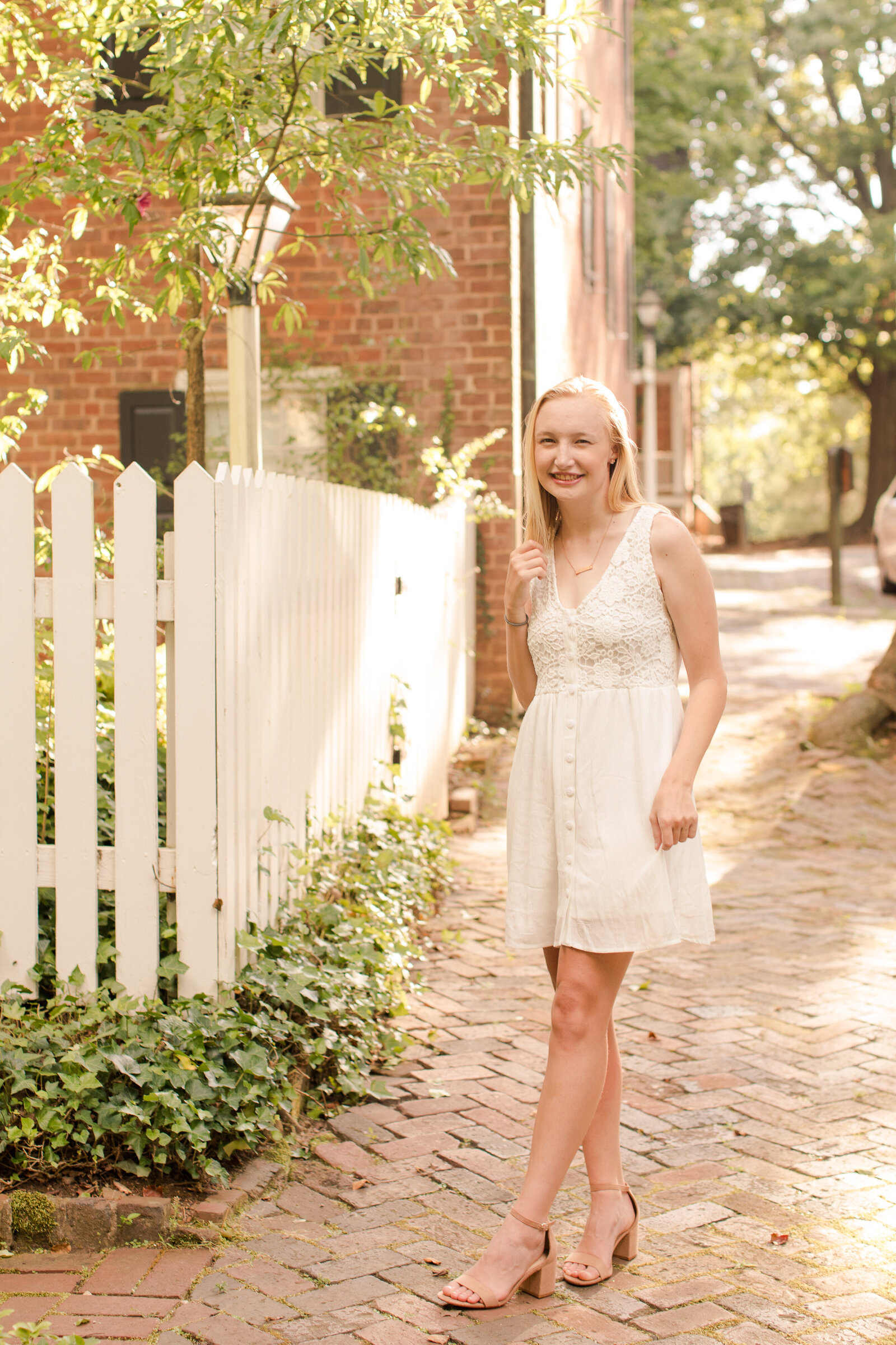 senior girl in a white dress on a brick sidewalk