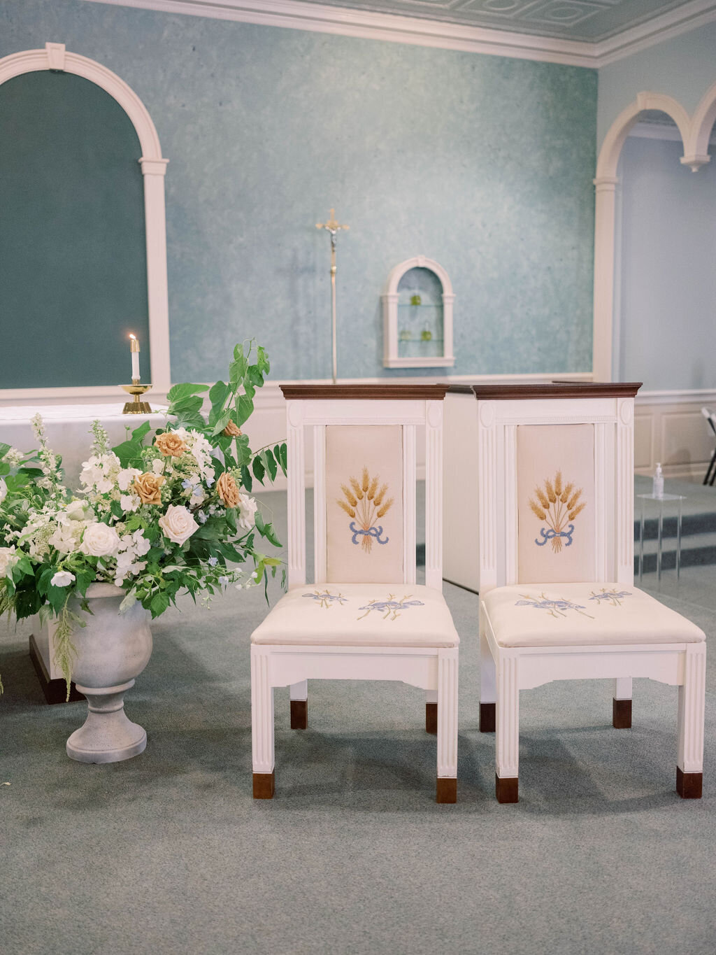 Alter arrangement in a tall urn with seasonal foliage, toffee roses, blush garden roses, white hydrangea and white larkspur and delphinium in Sacred Heart Catholic Church in Chestertown MD.