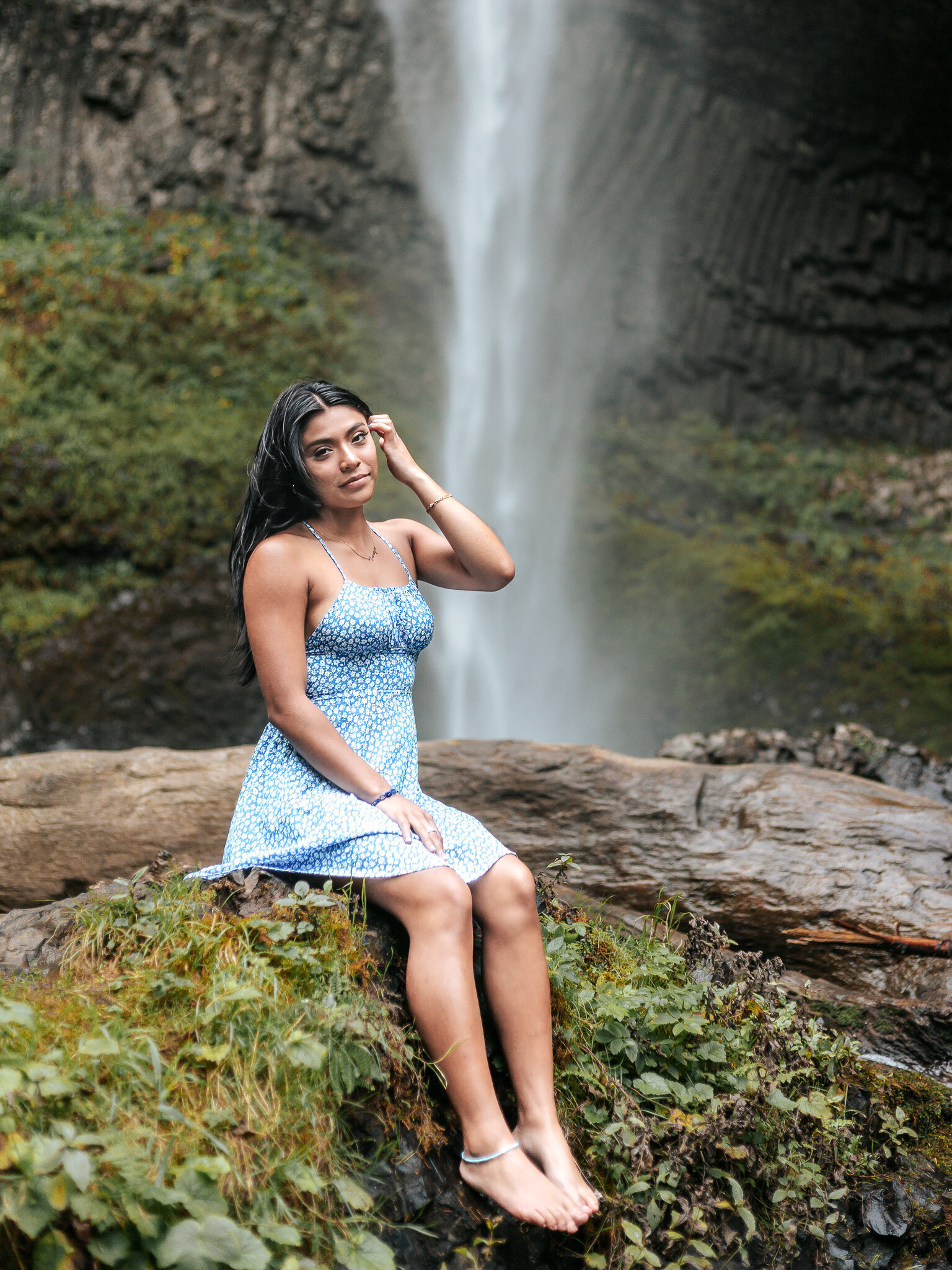 Girl sitting on rock at latourell falls with the falls cascading behind her