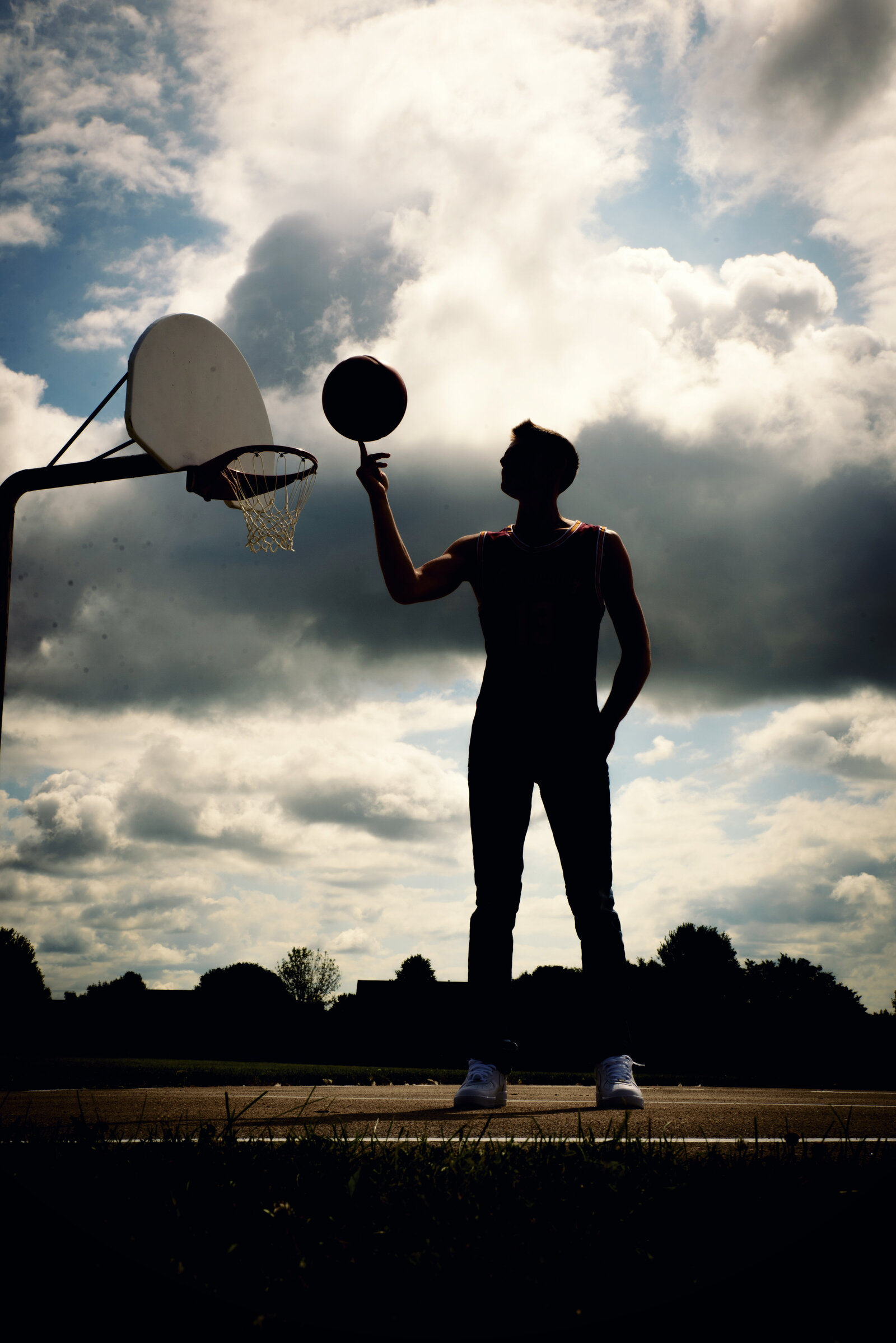 High school senior boy basketball pose in a Green Bay, Wisconsin park with a basketball court.