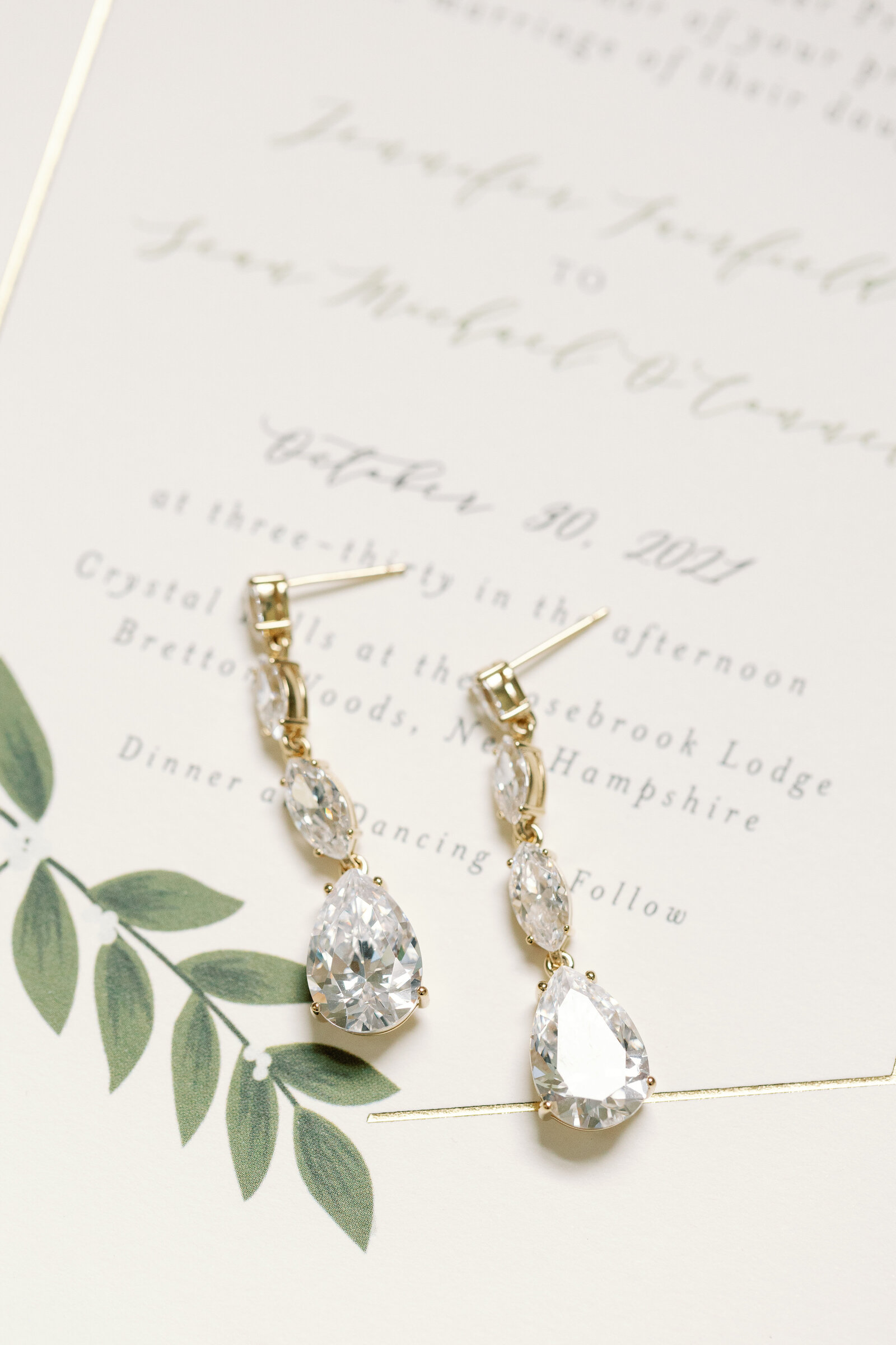 A close up view of earrings laying on a wedding invitation.