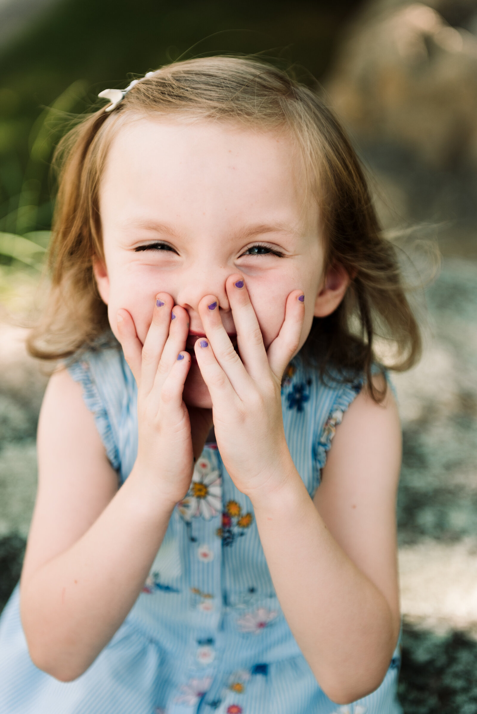 young girl laughing holding hands over mouth