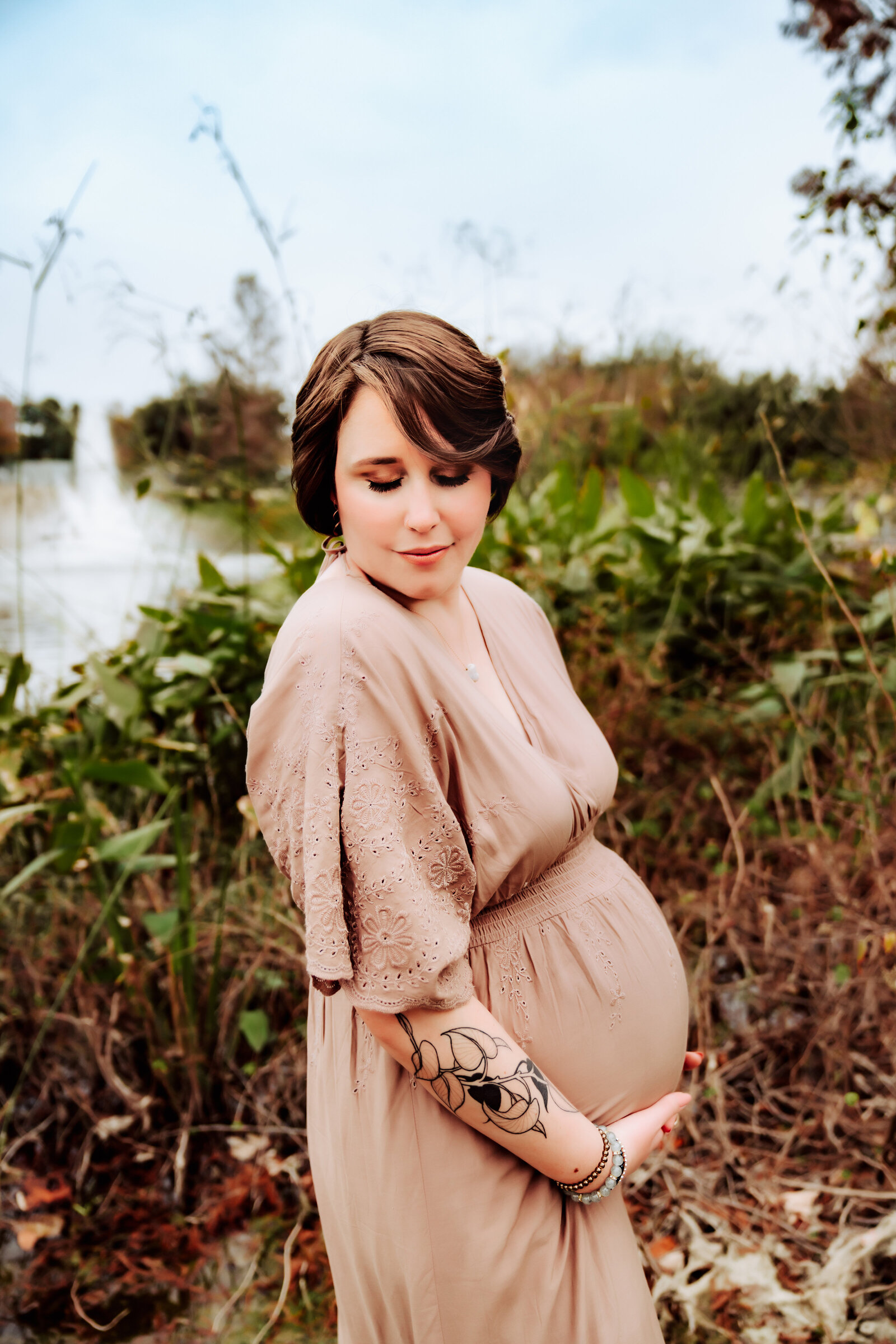 Maternity Photographer, a pregnant woman stands near the river bank