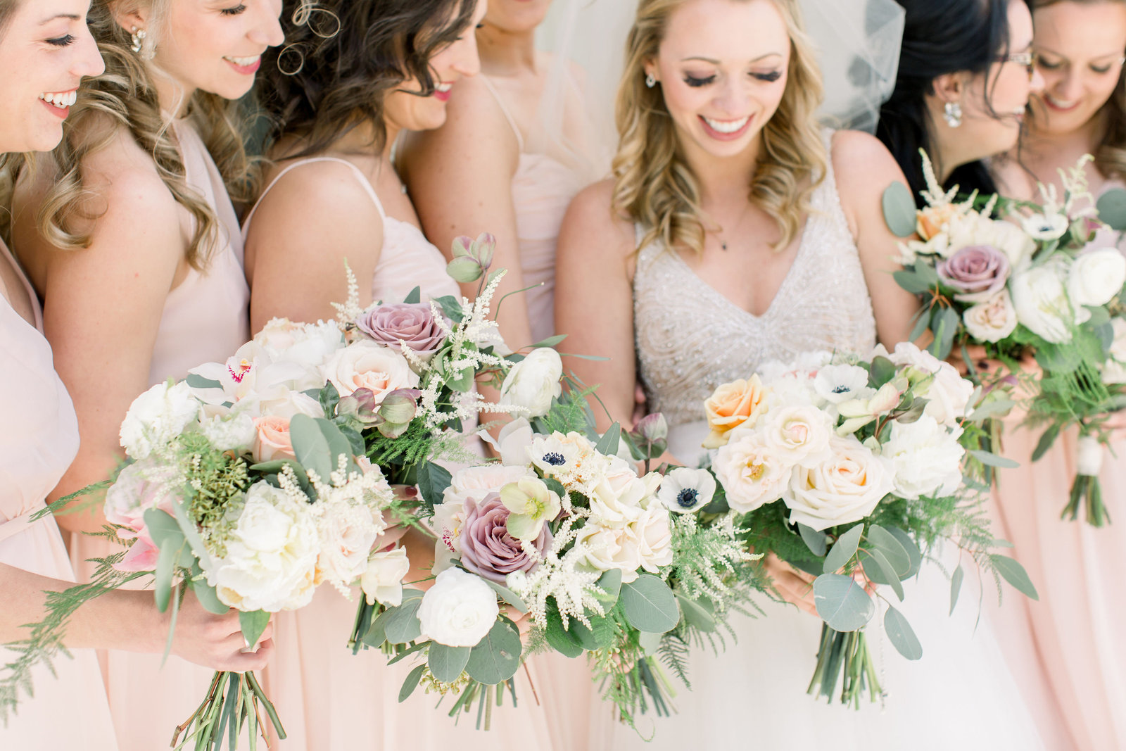 Bridesmaids and bride holding blush wedding bouquets