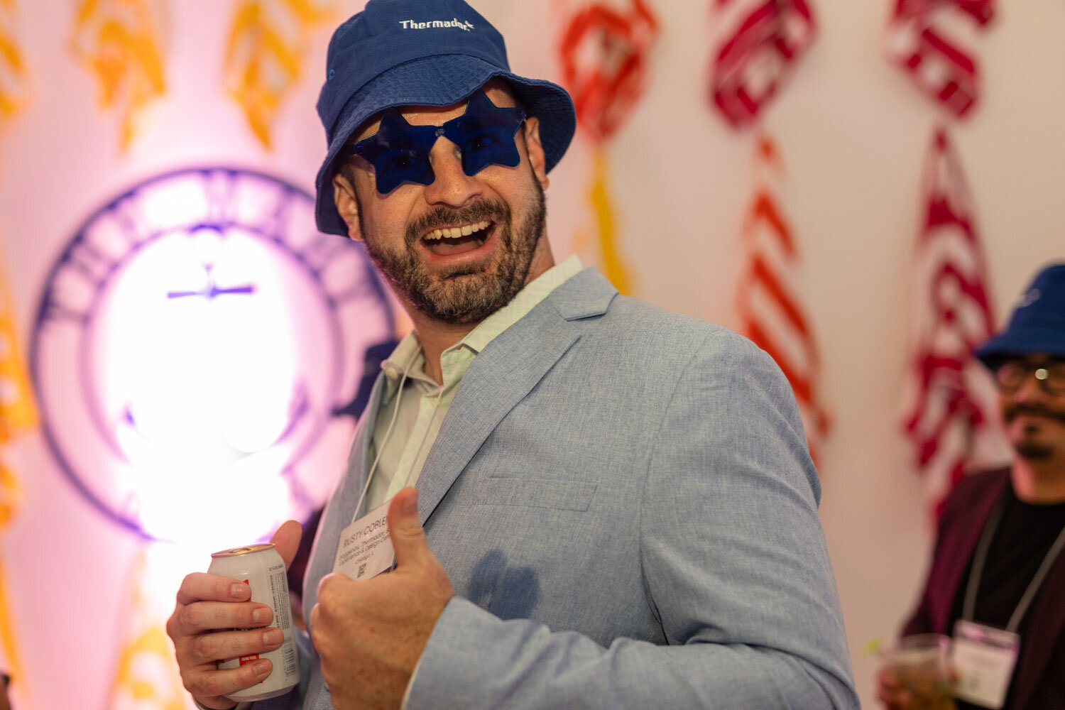 A man wearing a blue hat and sunglasses is giving a thumbs up