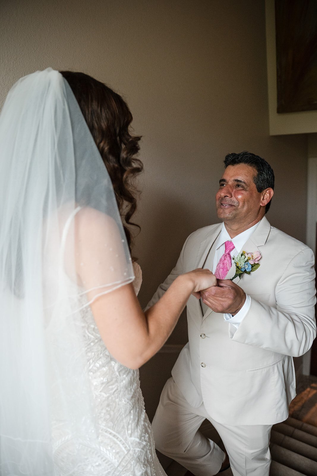 A touching moment as the groom helps adjust the bride’s dress before their wedding ceremony, captured by CMH Studios.