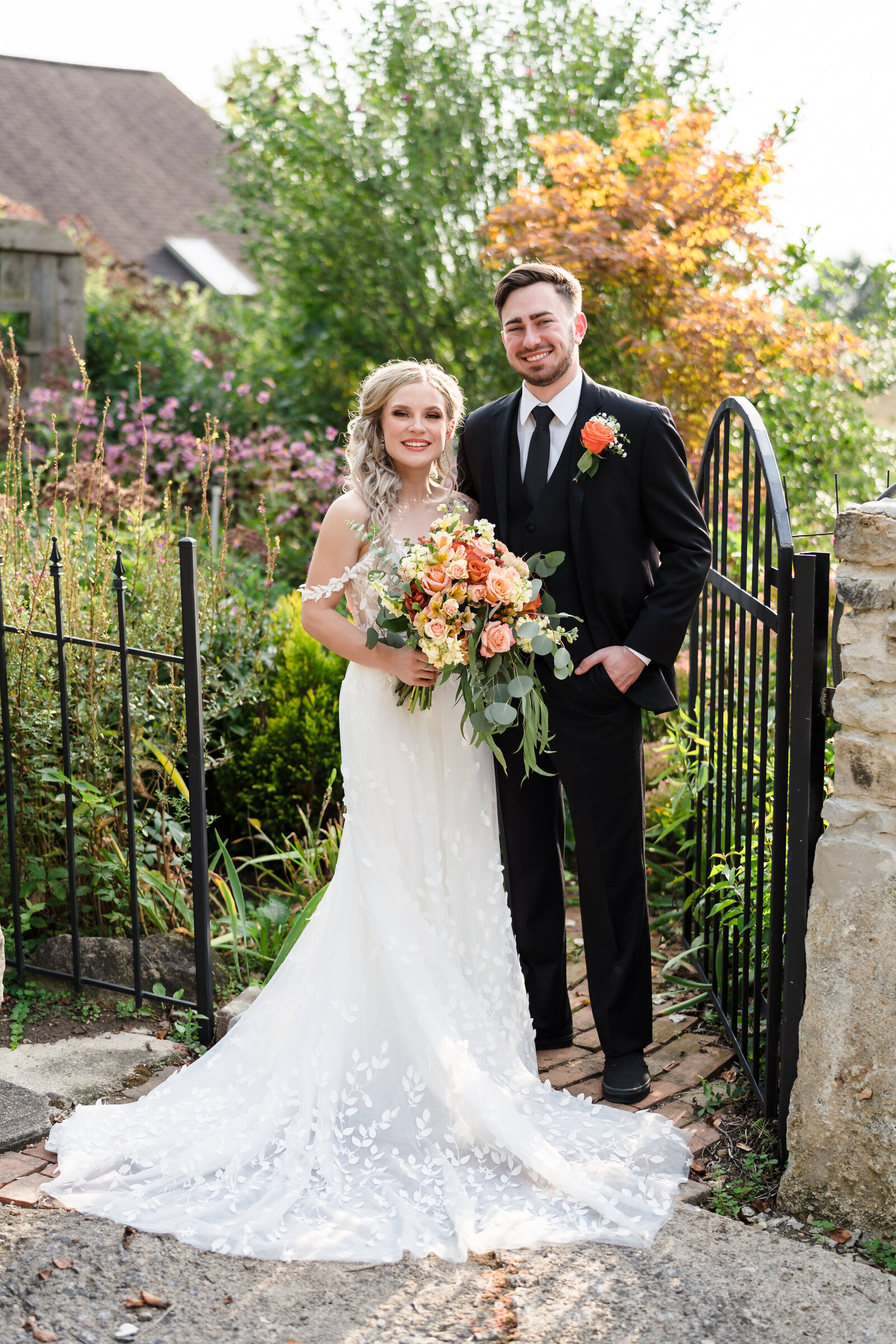 Bride and groom smile while basked in golden light and surrounded by wild flowers