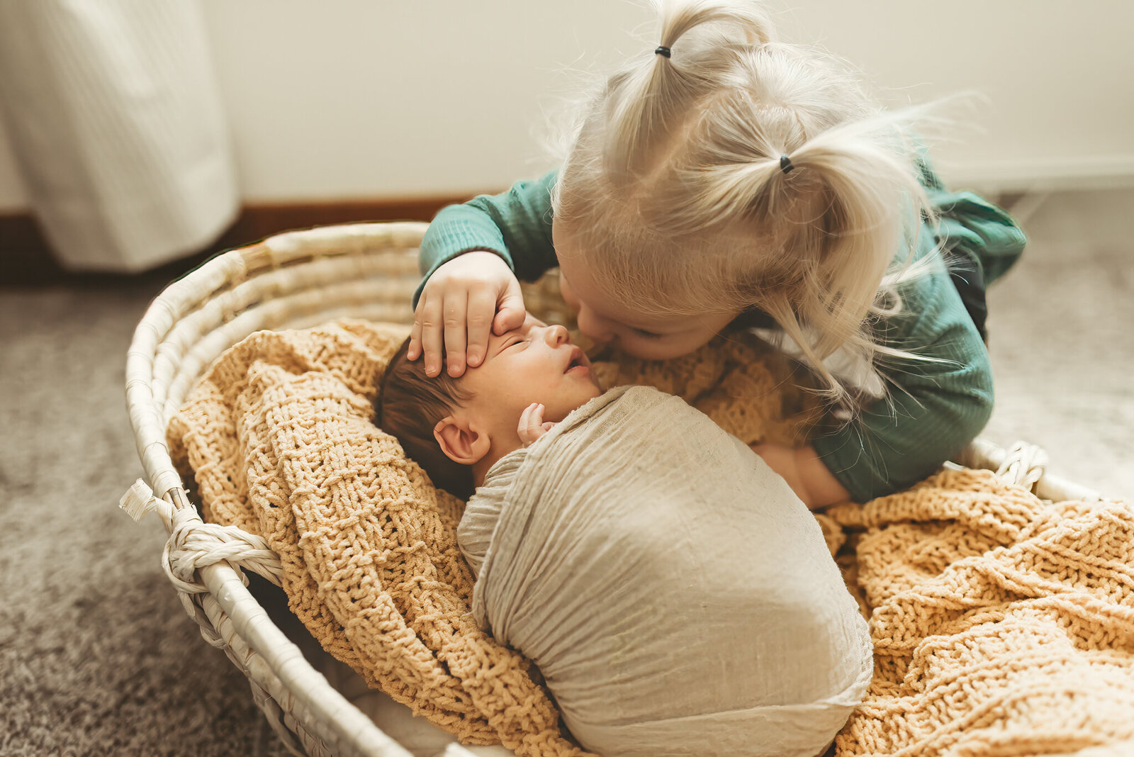 Big sister gives her little brother a sweet kiss during an in-home newborn session in Mandan, ND