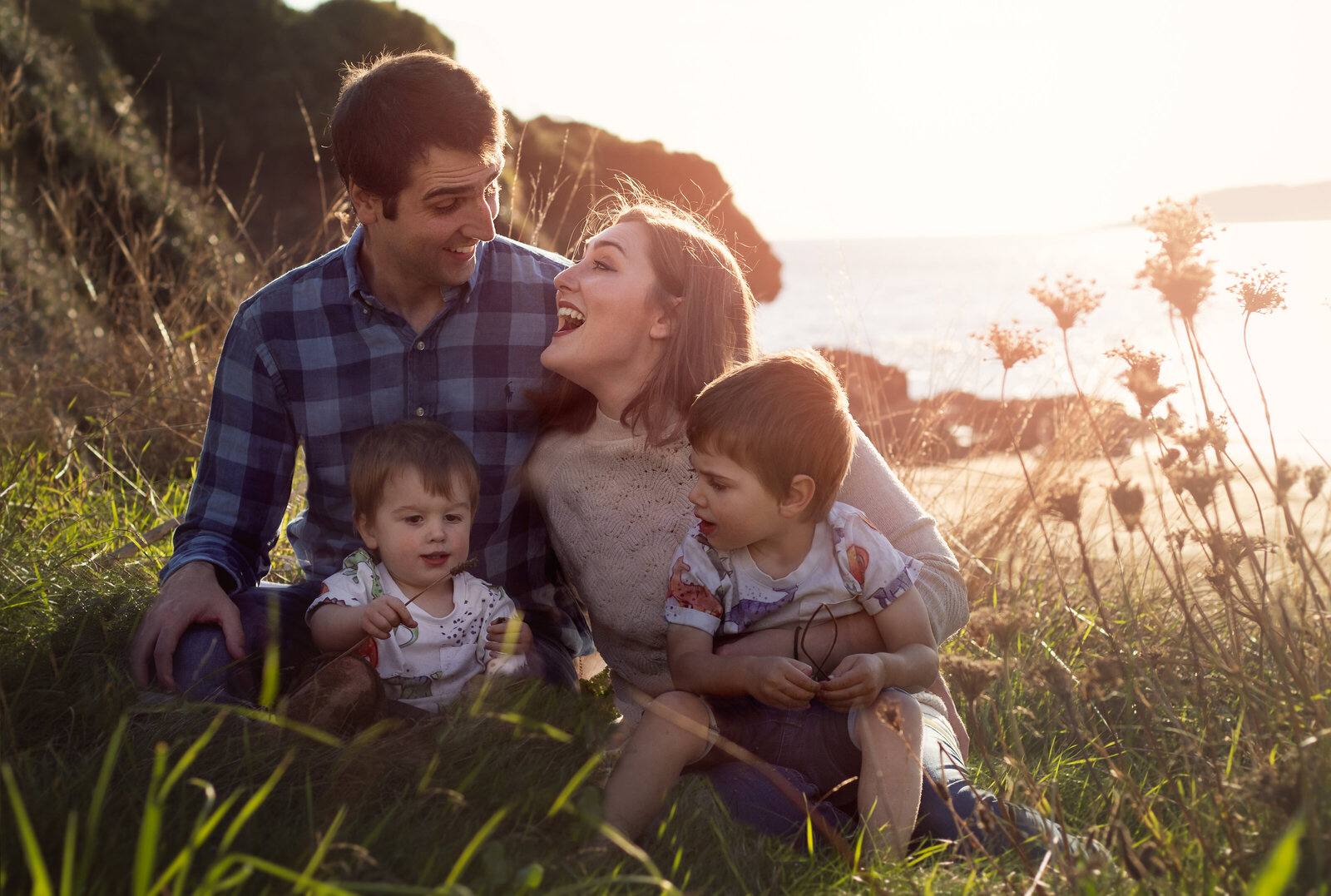 Family of four cuddle during beach photography session