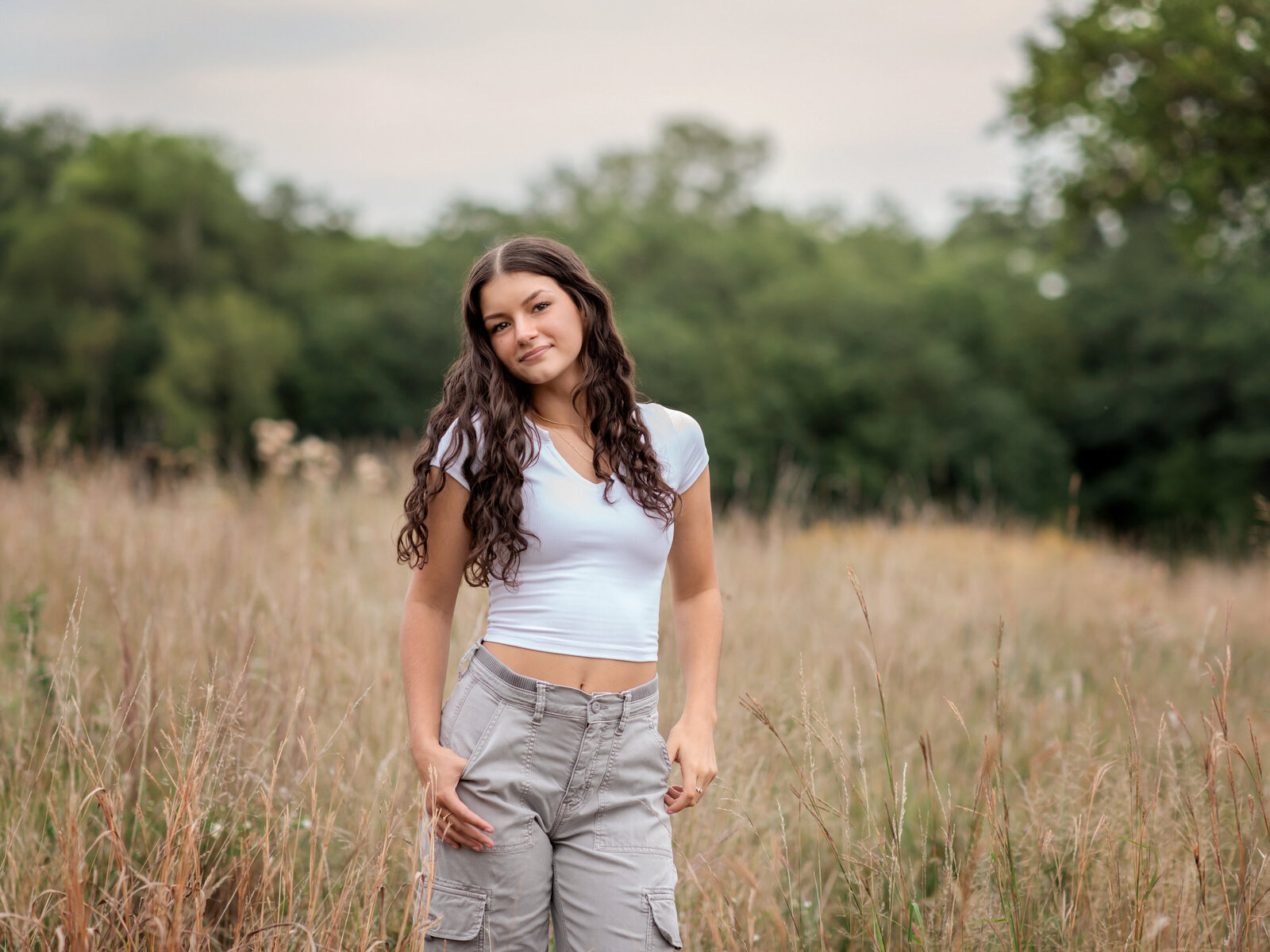 senior girl posing in field for senior photos