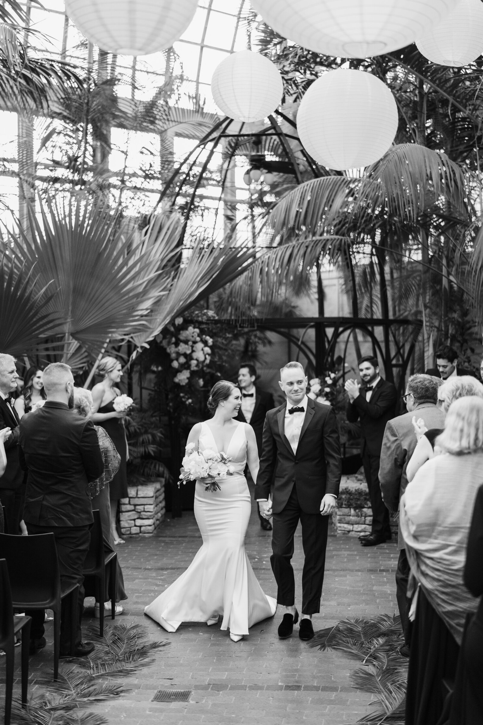 Bride and groom recess down the aisle after their first kiss in the Palm House