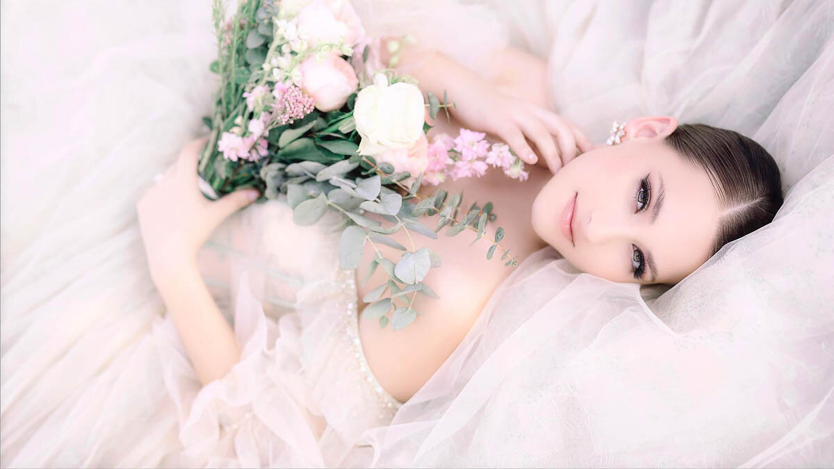 luxurious photo of bride against her tulle wedding dress train holding bouquet