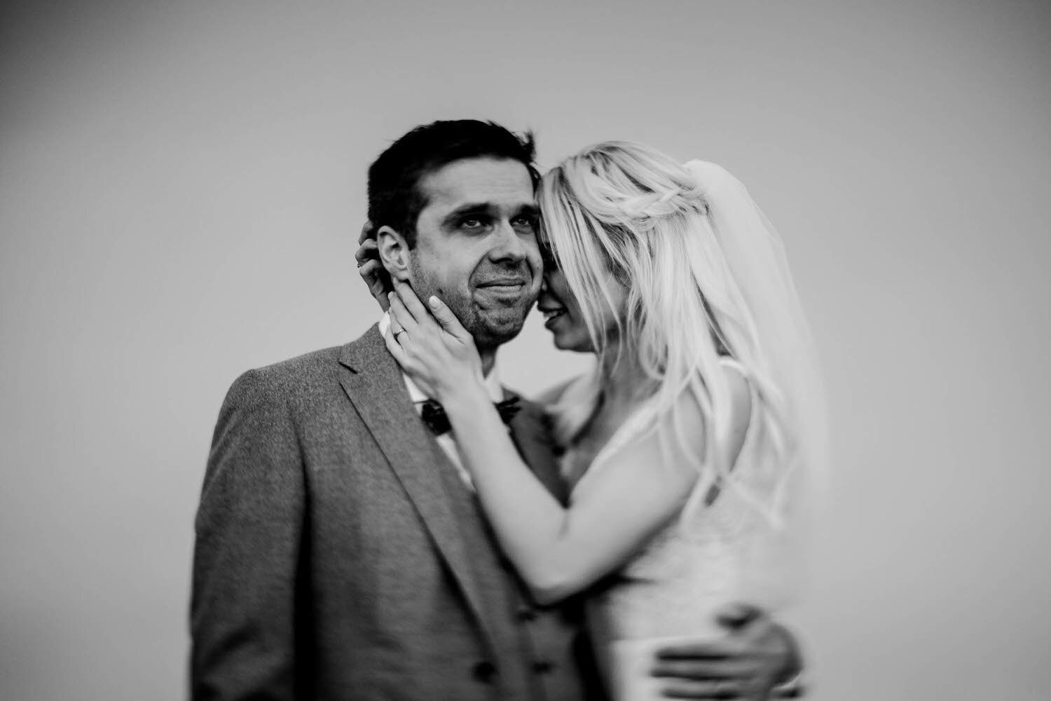 black and white photograph of a bride and crying groom in portrait.