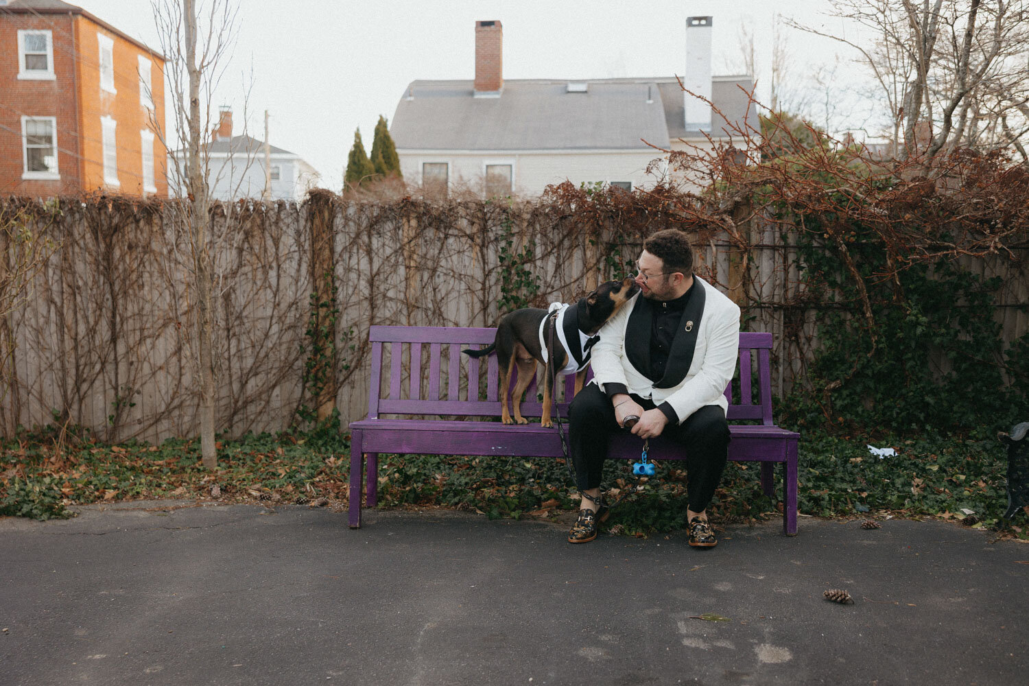 Groom sitting down on an outside chair with his dog