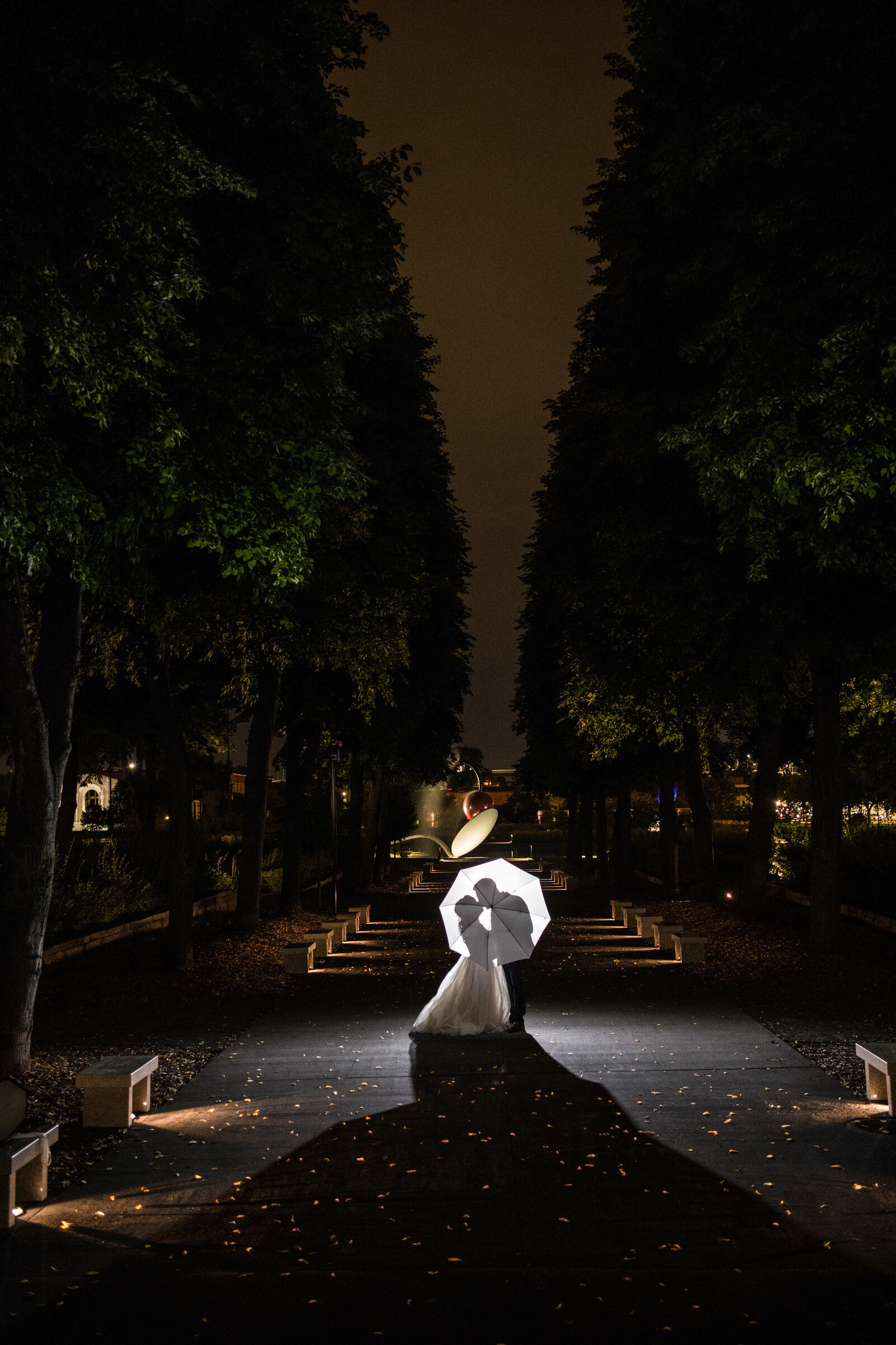 Bride and groom kiss at night in front of the Spoonbridge and Cherry in Minneapolis, Minnesota.