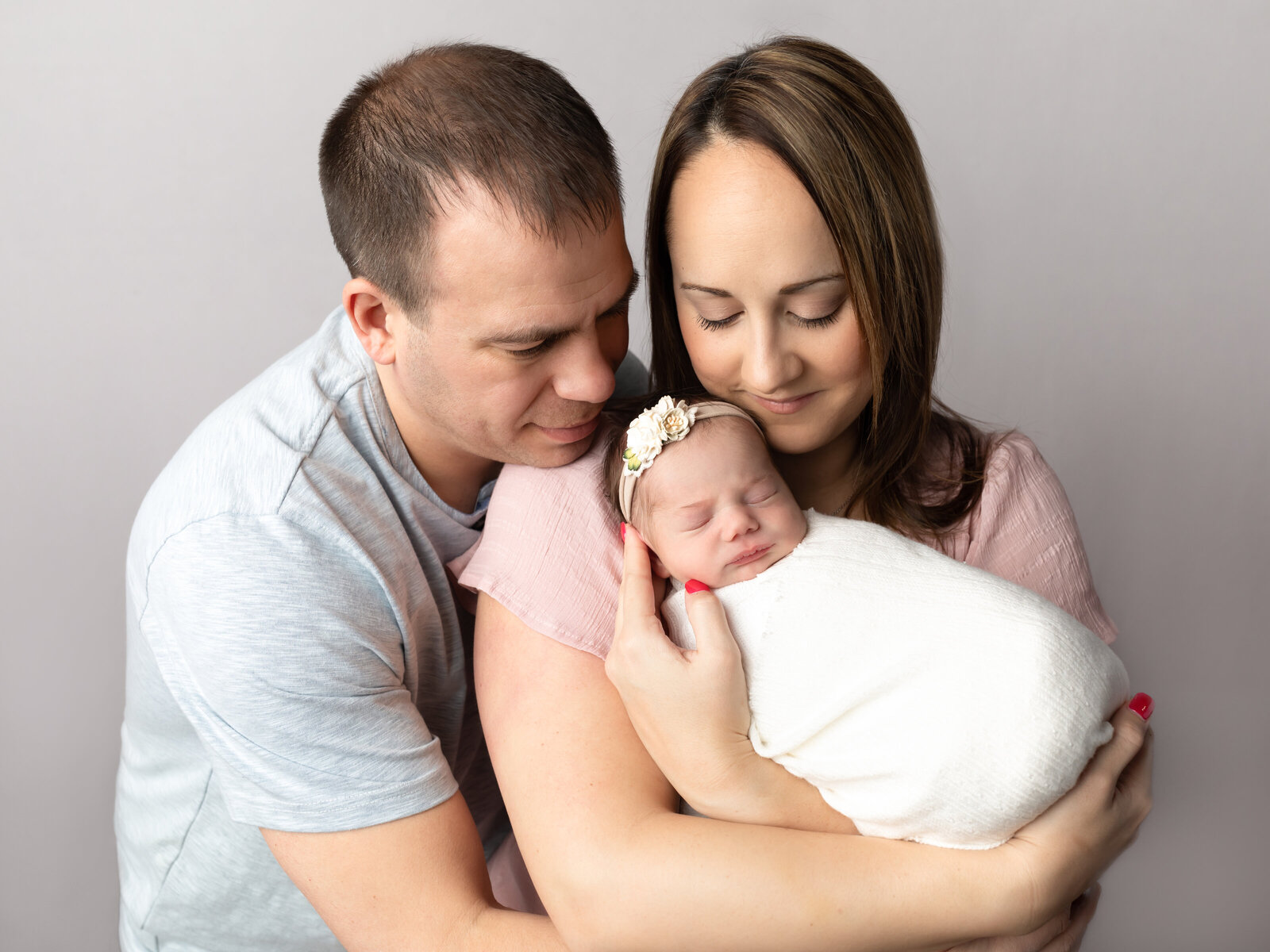 mom and dad holding newborn baby girl for photoshoot