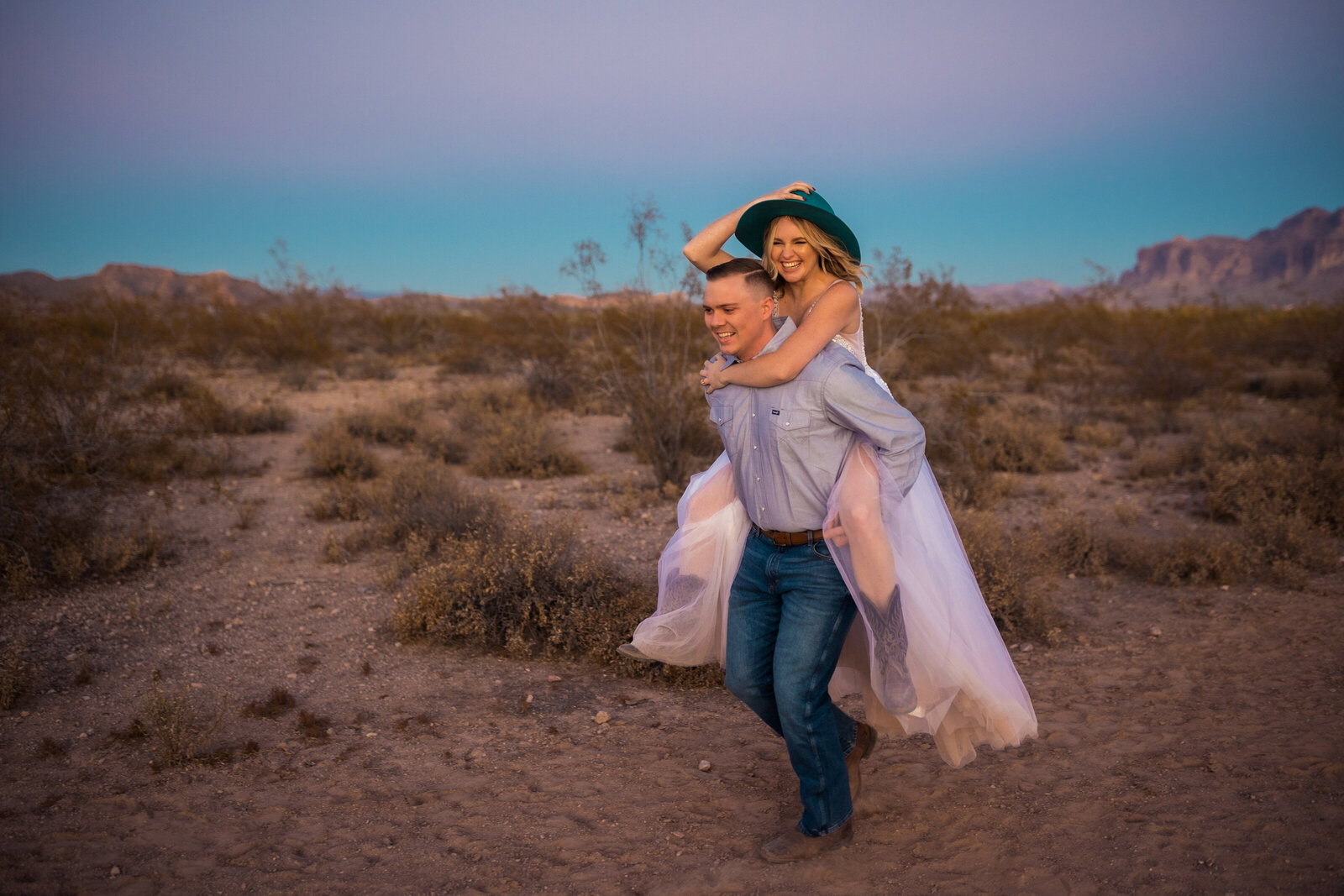groom giving the bride a piggyback ride in the desert