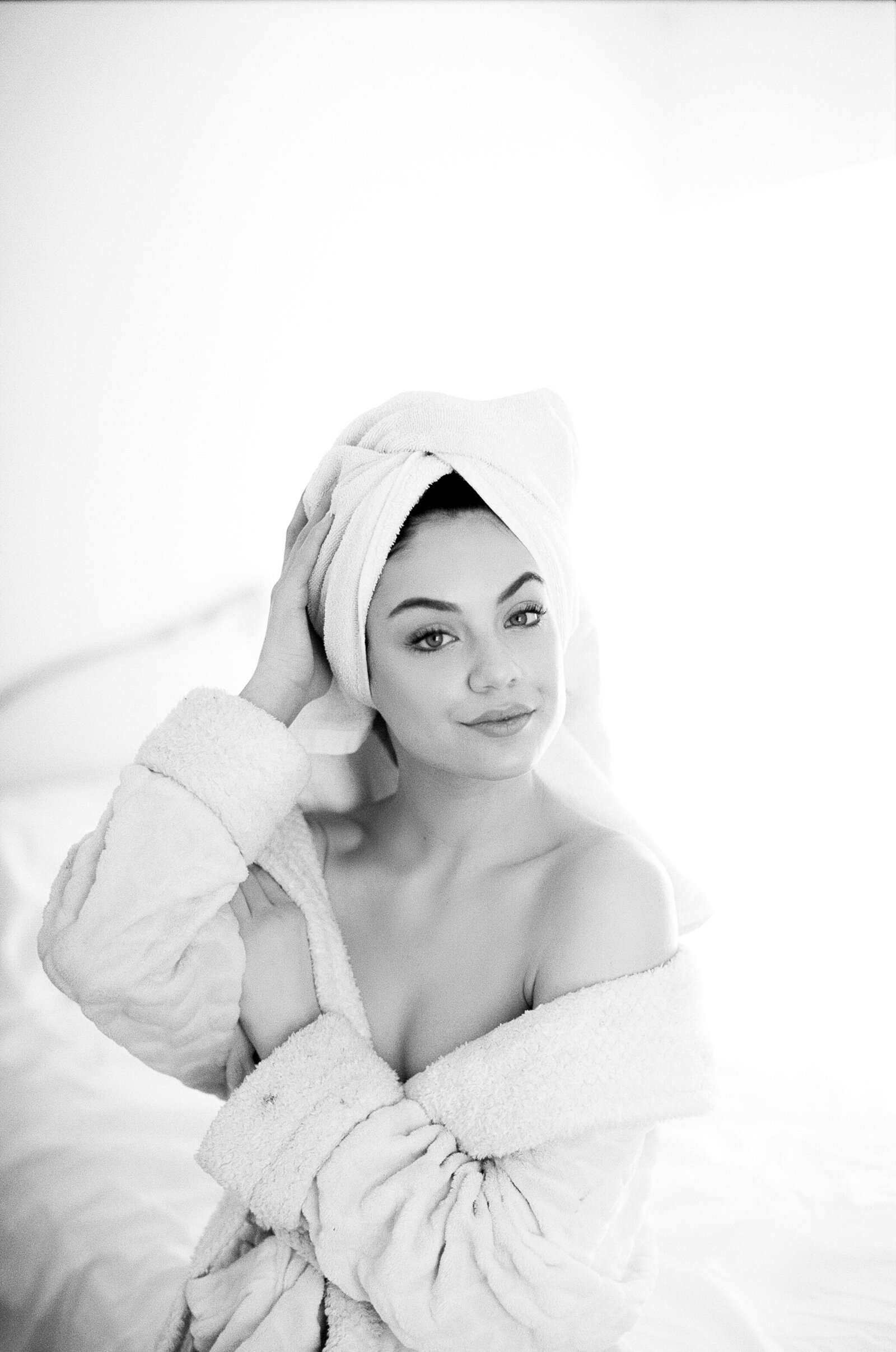 Black and white boudoir photo of woman wearing bathrobe and towel on head
