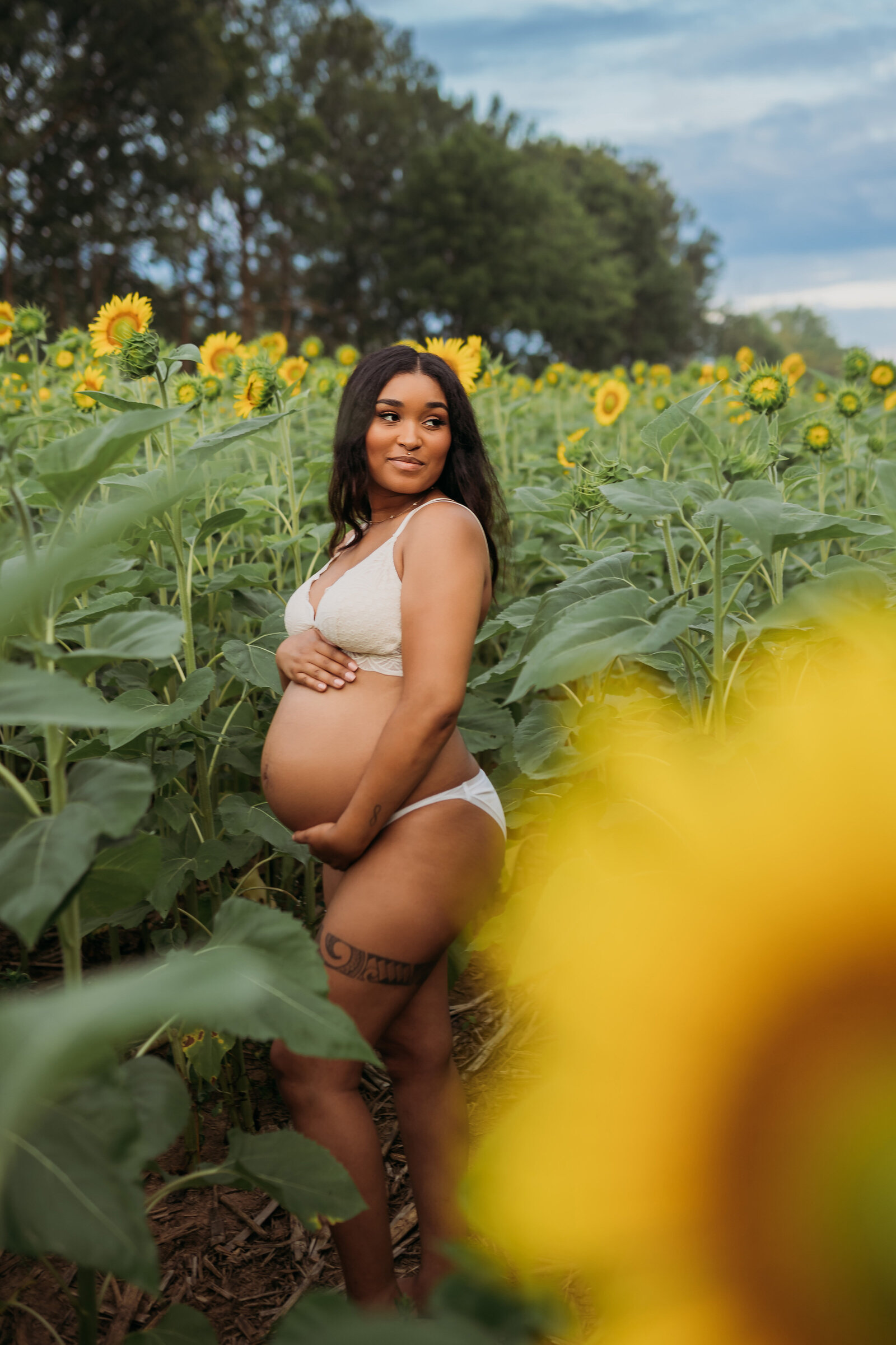 mom poses in sunflower field for maternity session in Tampa