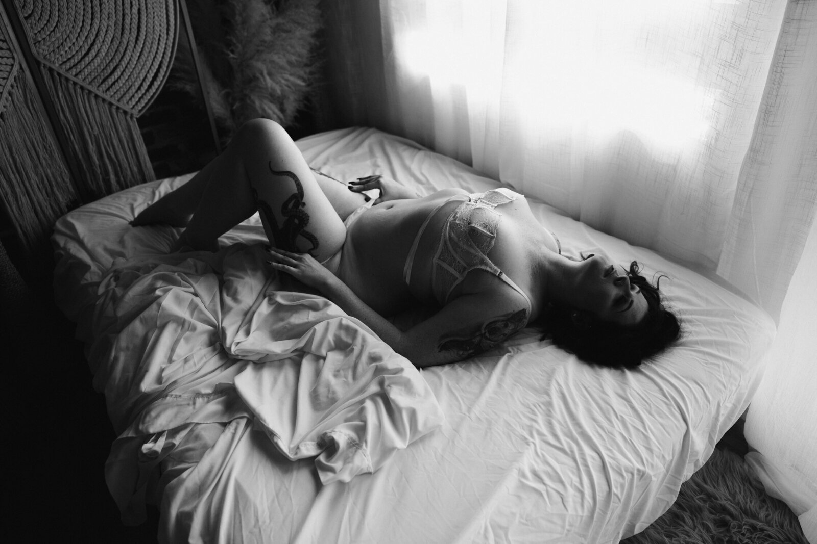 Black and White full body of women laying in white messy sheets
