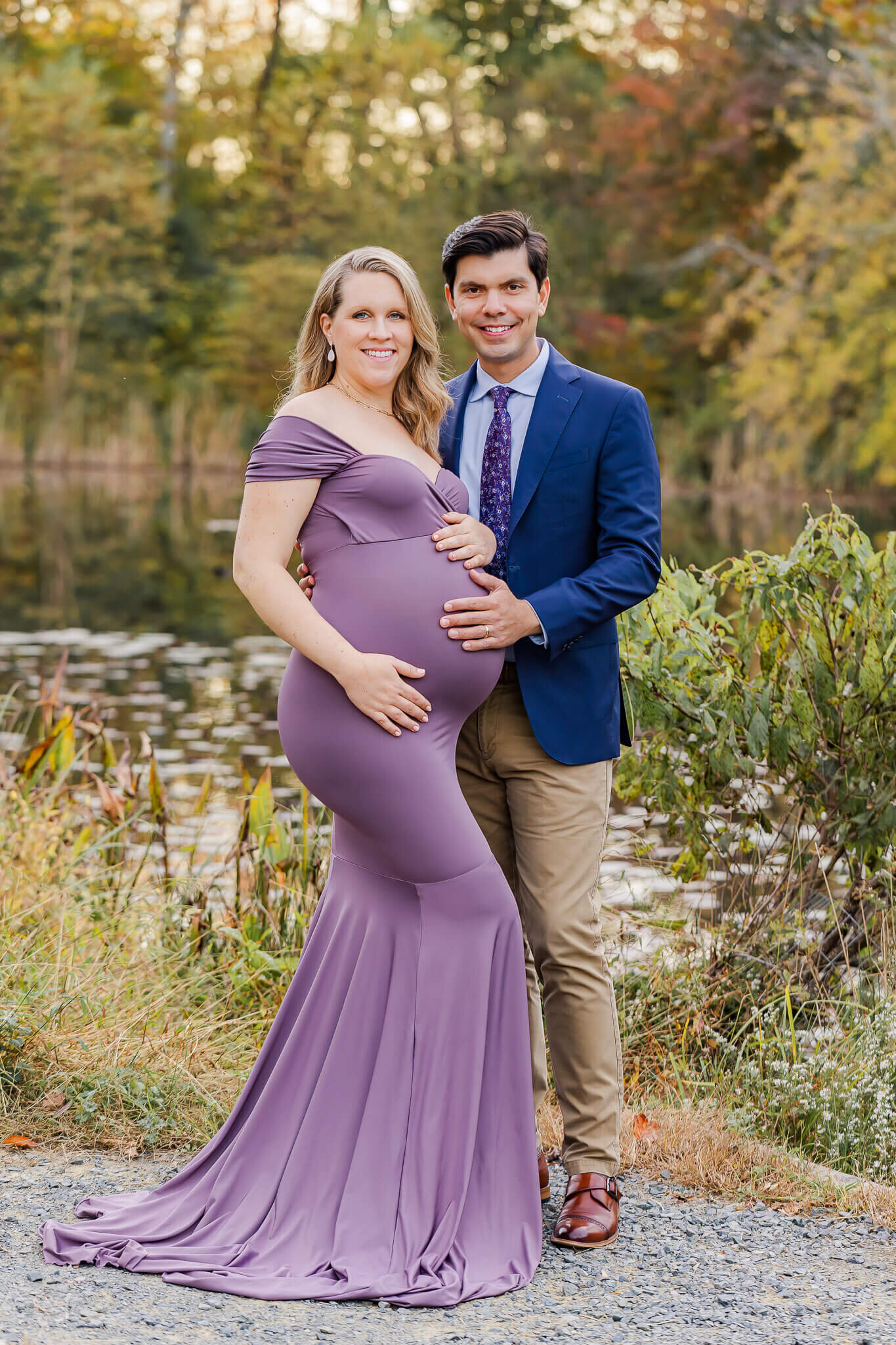 A maternity portrait session of a woman in purple with her husband.