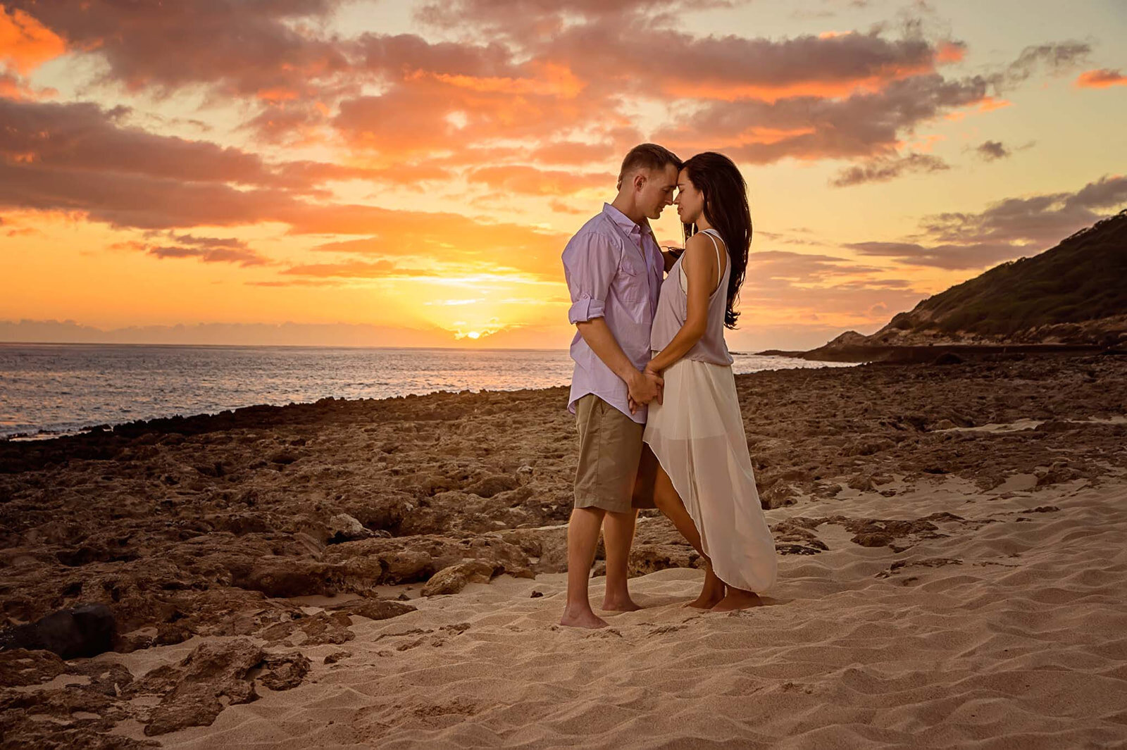 A couple sharing an intimate embrace at sunset by the beach, captured during their destination wedding by CMH Studios