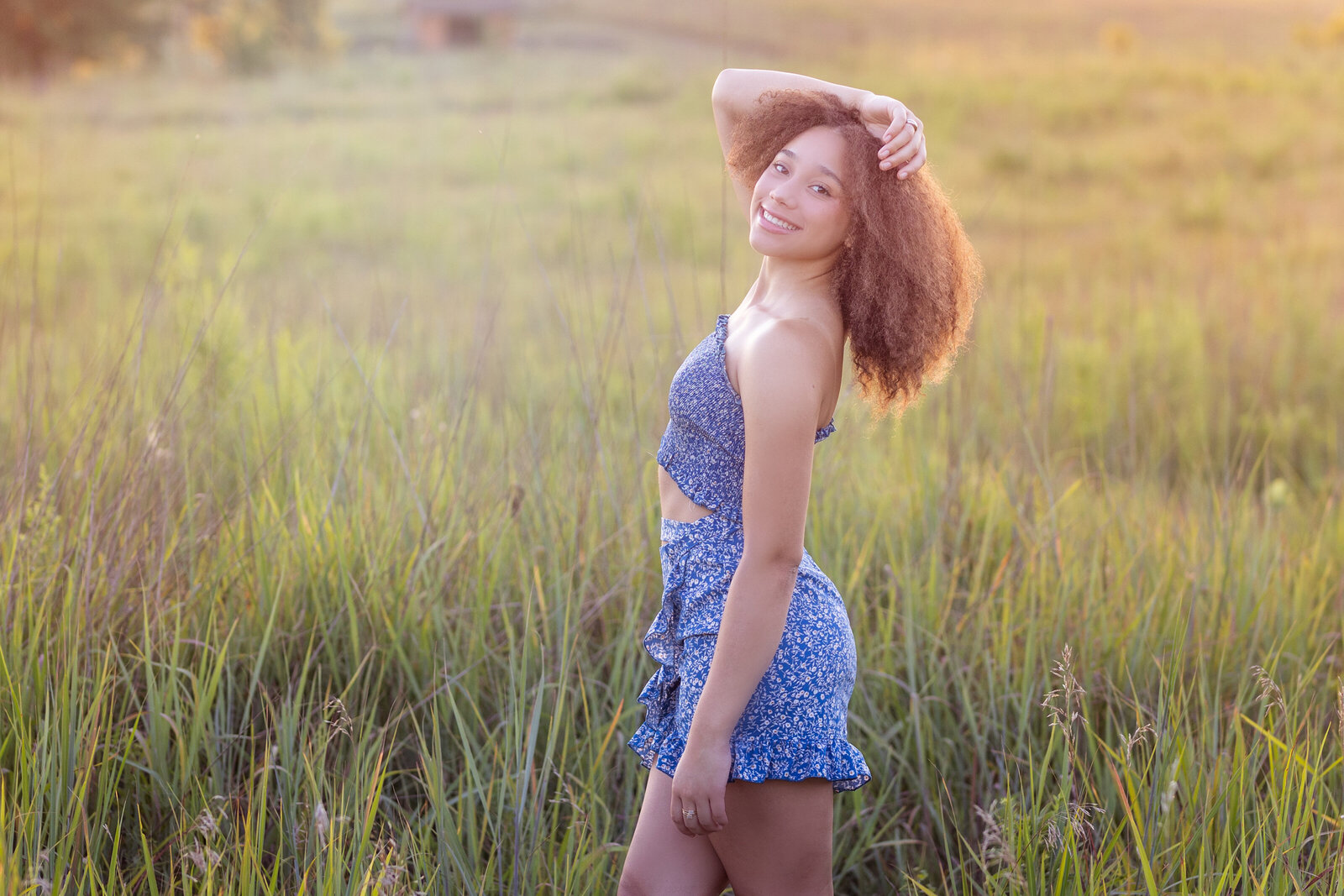 Amanda stands in tall sunlit grass