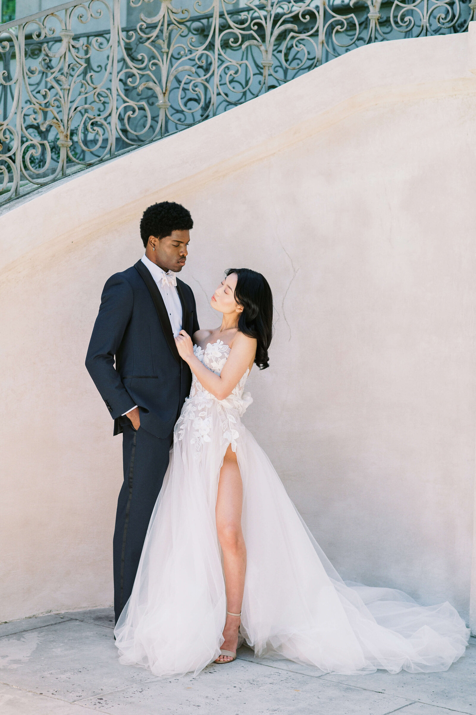 A mixed race couple pose together during their couple's portraits at their wedding